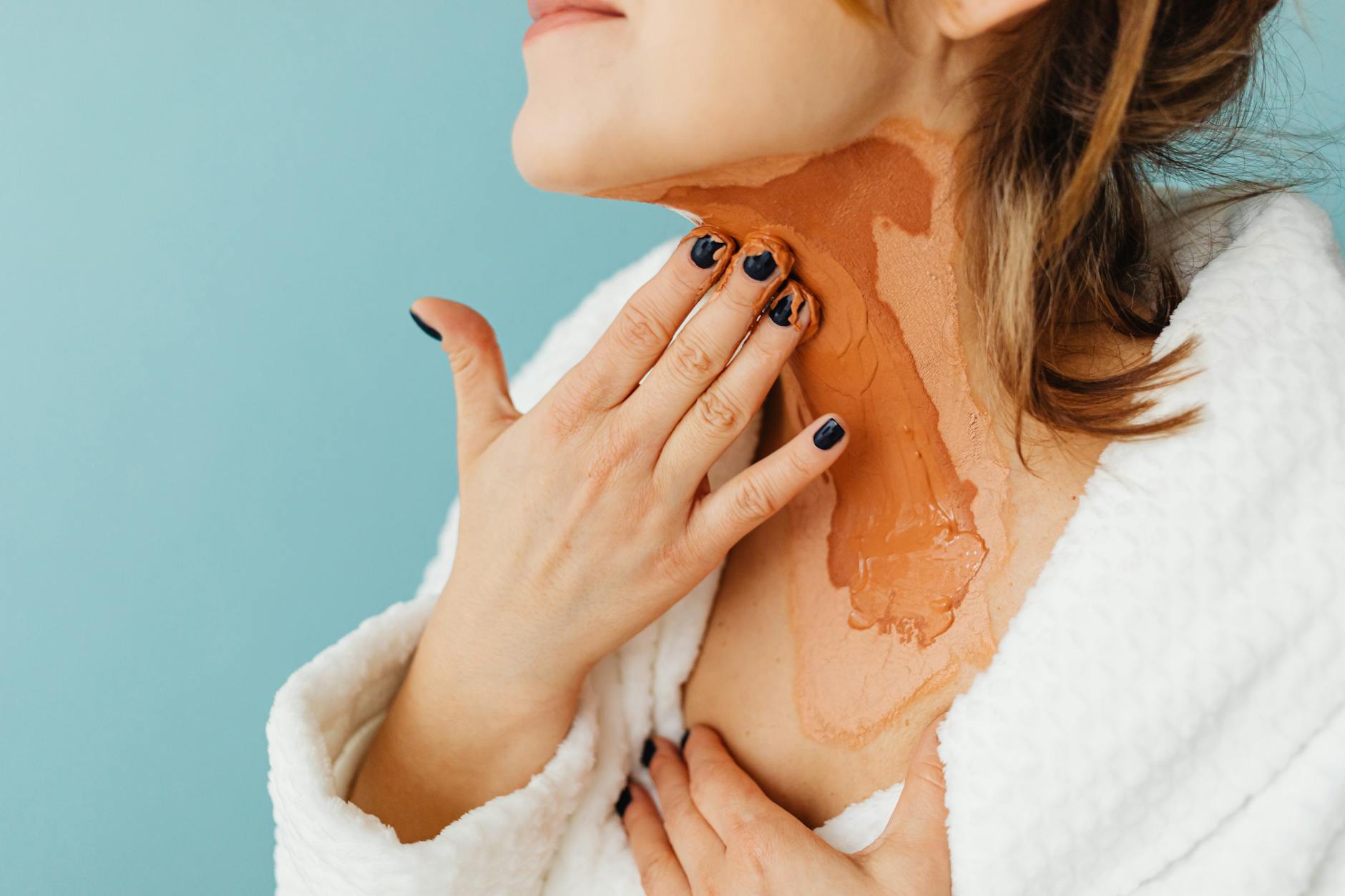 Close-up of a woman applying a skincare mask to her neck in a studio setting. - radiant skin foods