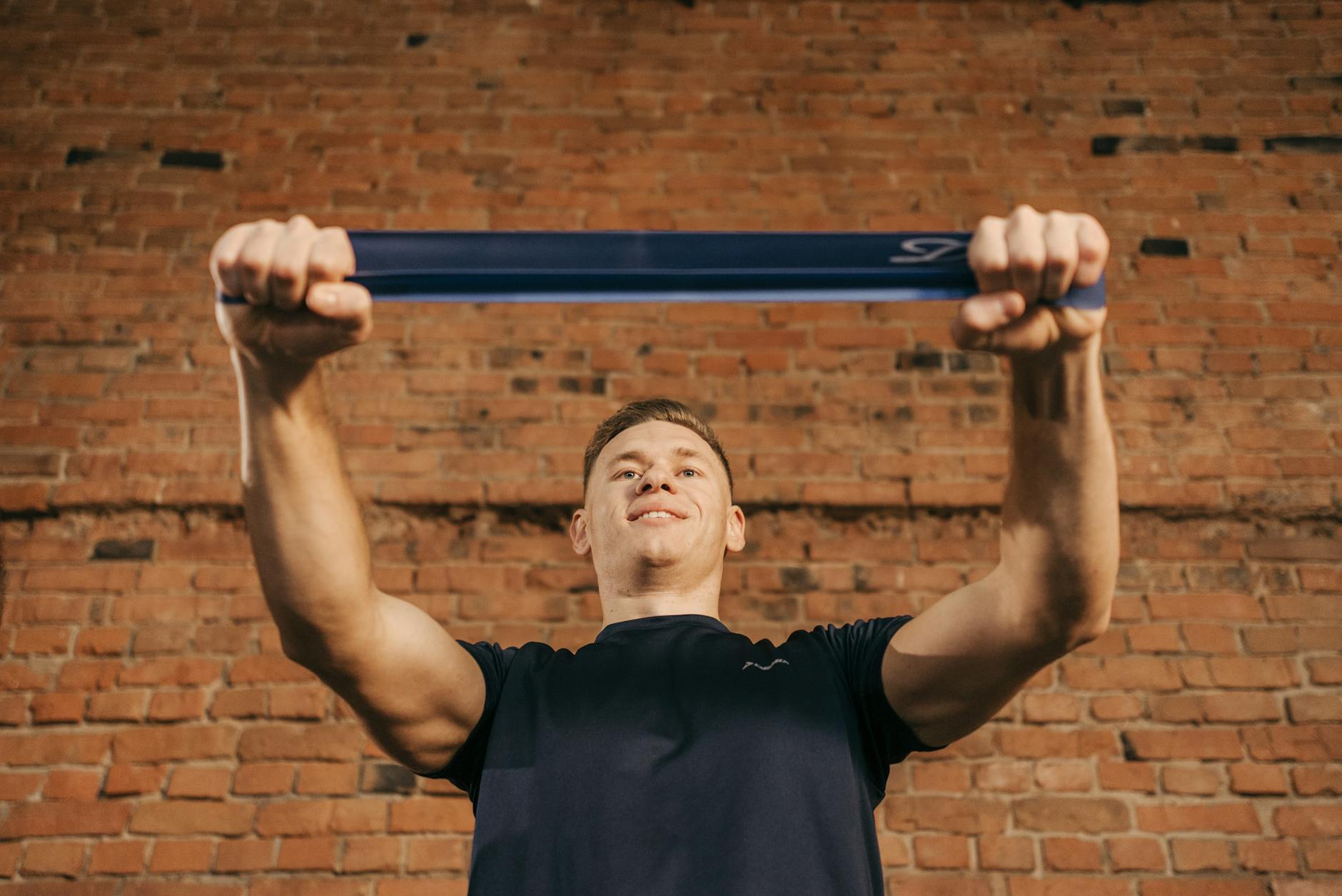 Man performing workout with resistance band against a brick wall backdrop. - resistance band upper body
