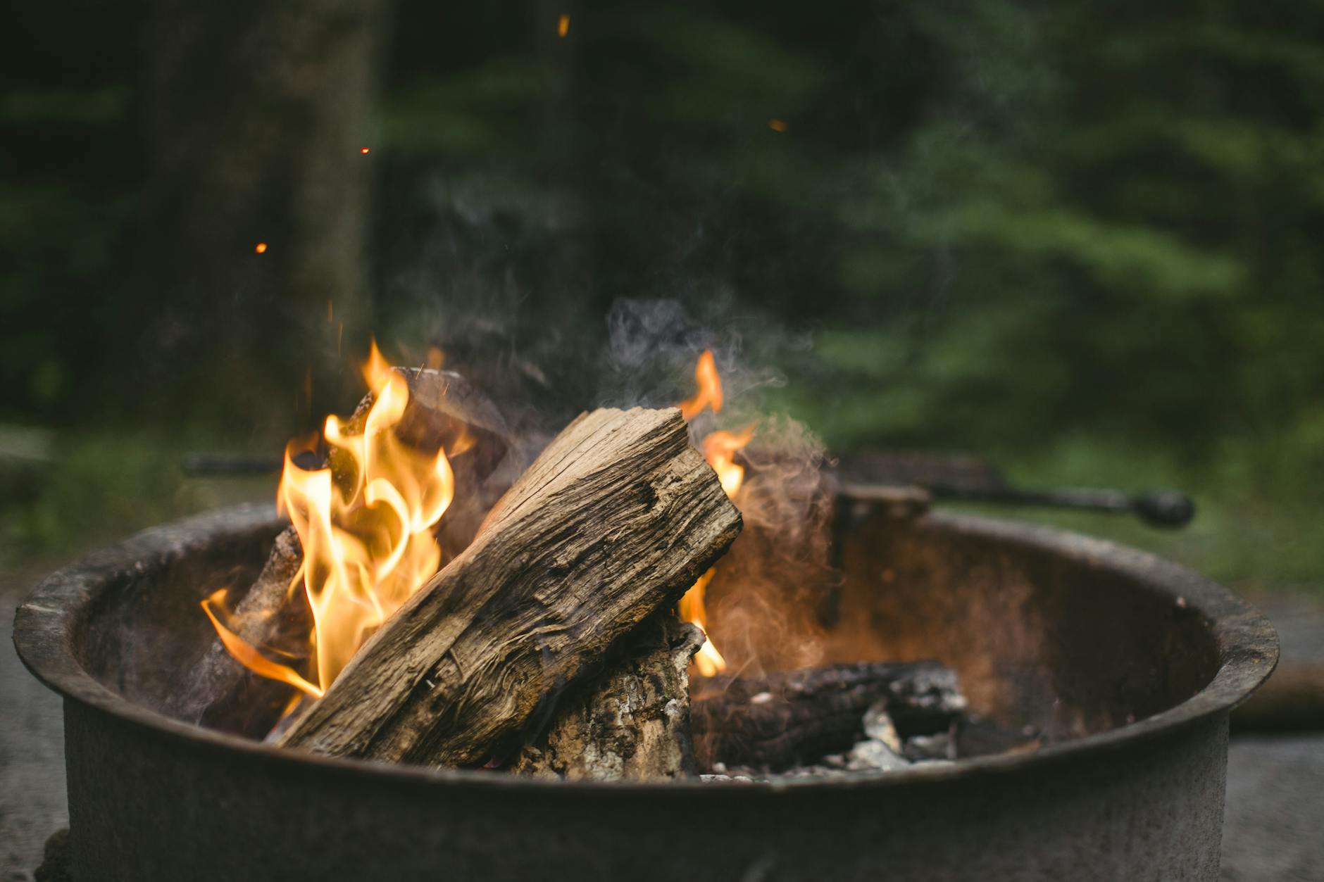 A cozy campfire burning with bright flames in a metal pit, perfect for a night outdoors. - spring calorie burning hikes