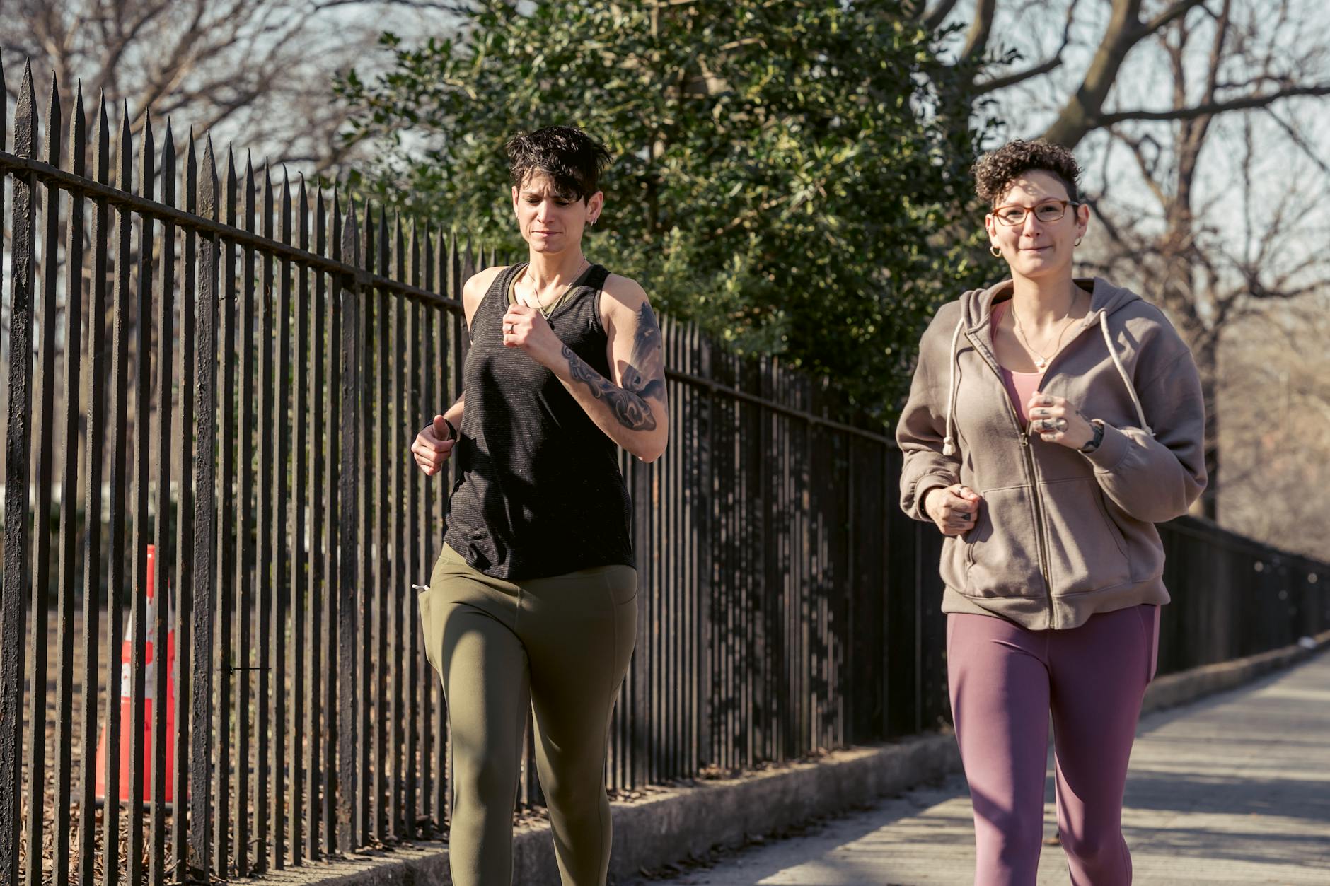 Two women jogging together in a city park, promoting fitness and active lifestyle. - spring cardio outdoors