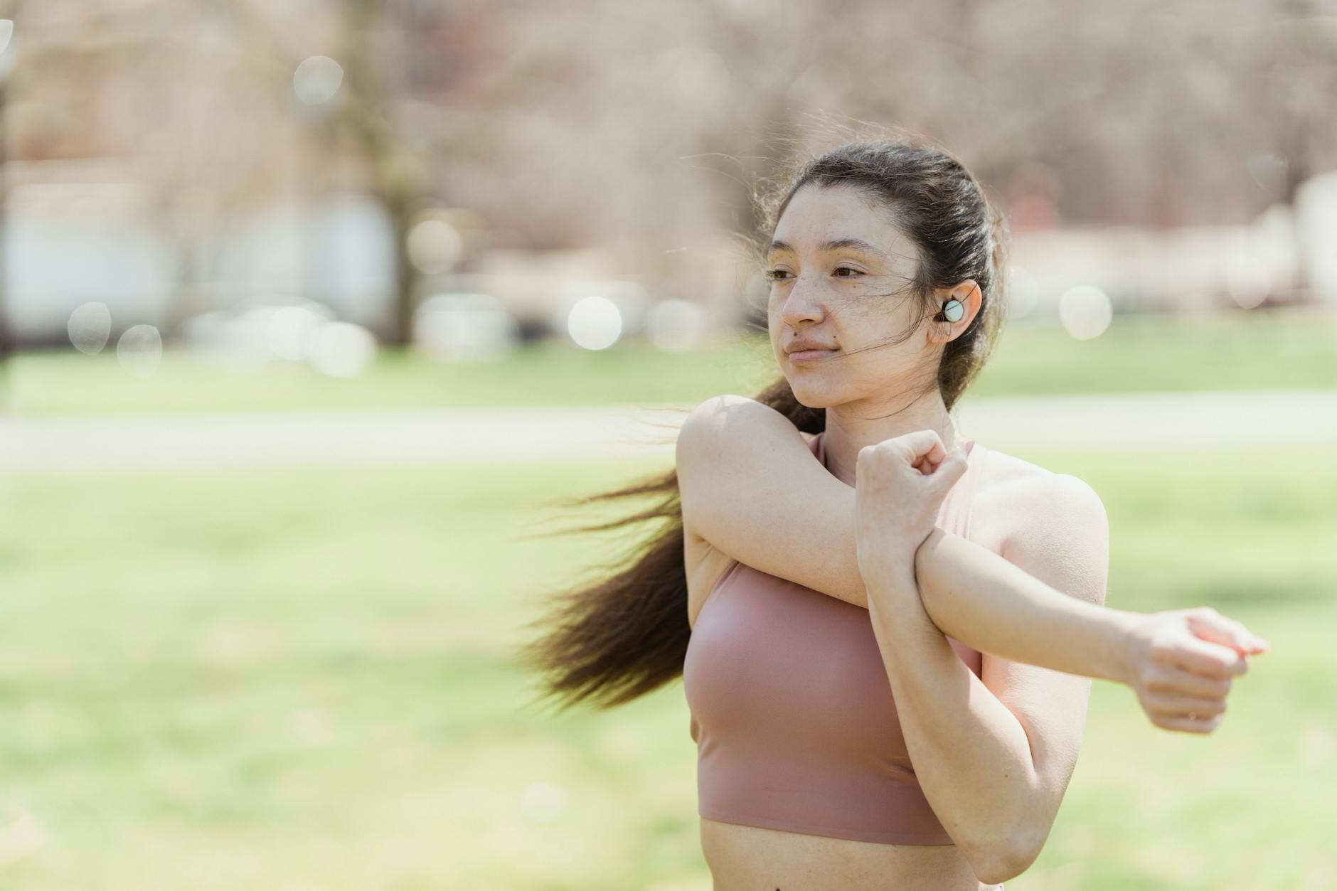 A young woman in activewear stretching outdoors, promoting fitness and healthy lifestyle. - spring hiit workouts