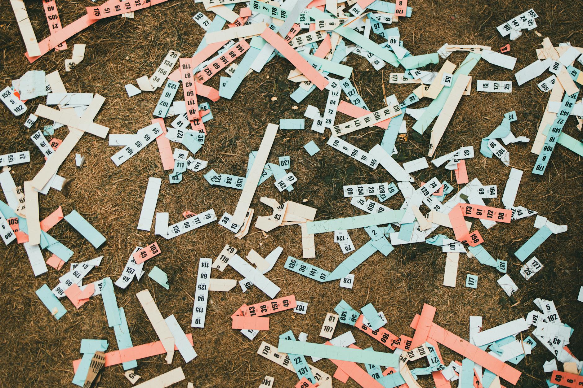Scattered numbered paper strips in pastel shades creating an abstract pattern on dry ground. - spring mood disorders