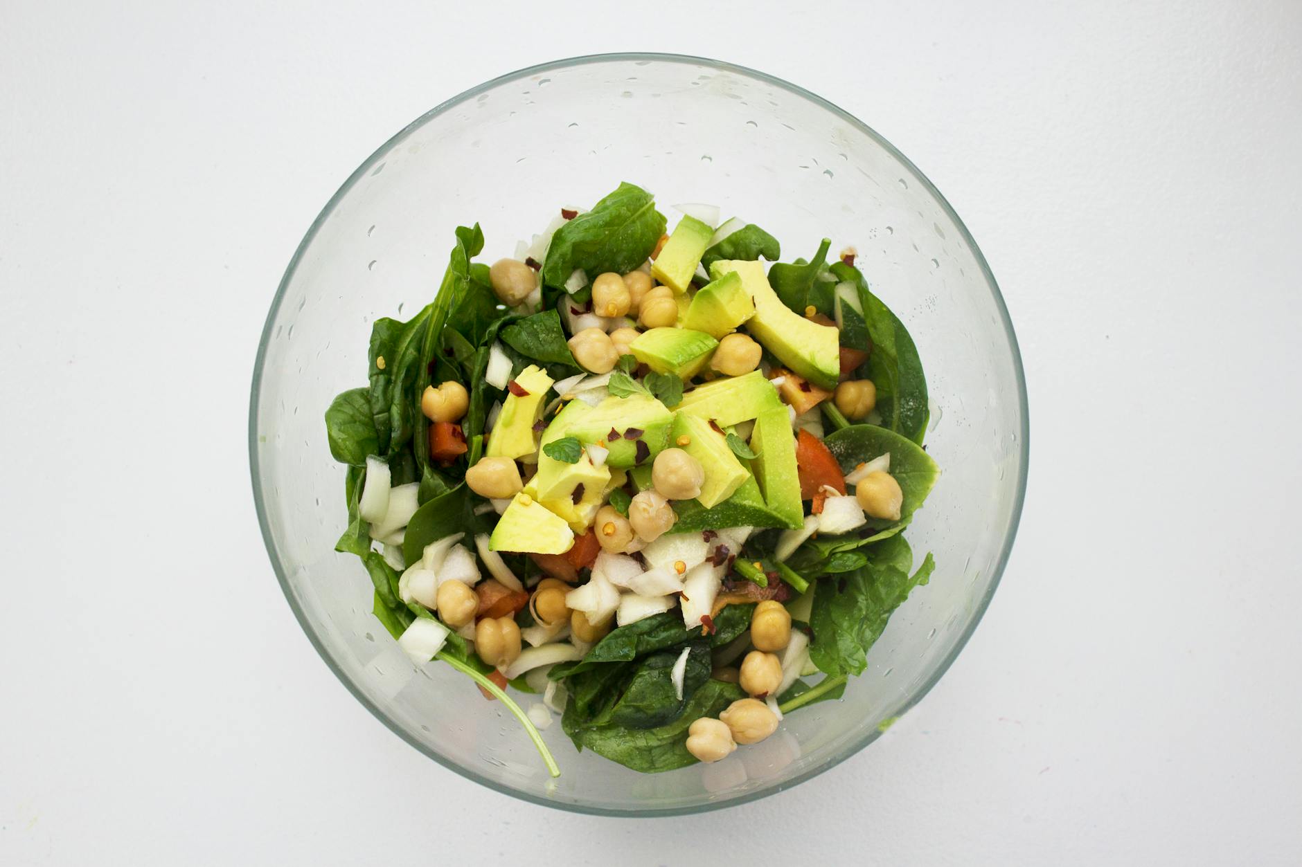 Fresh spinach salad featuring avocado and chickpeas, perfect for healthy eating. - spring plant based salads