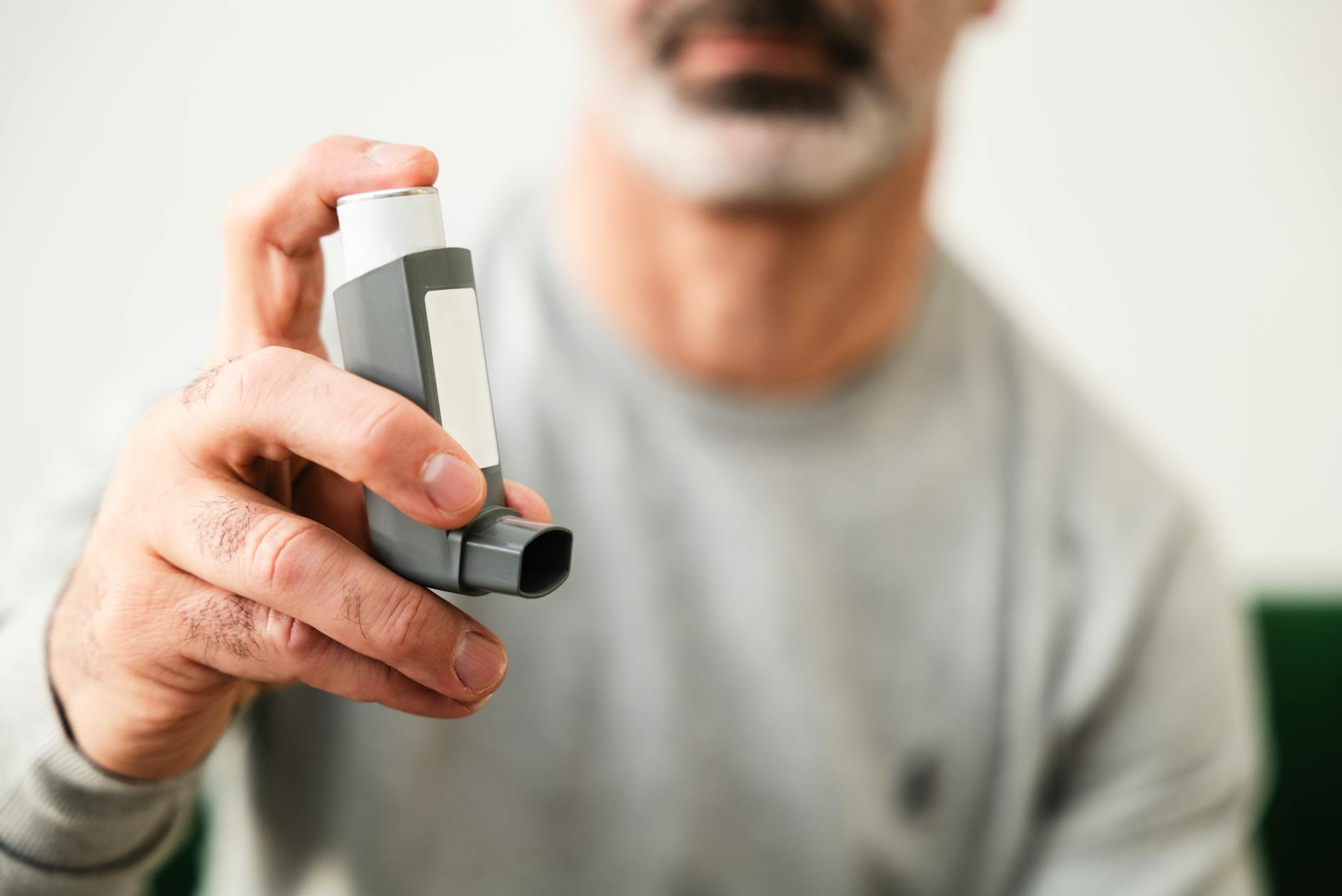 Man using an inhaler for respiratory health indoors. - spring pollen allergies