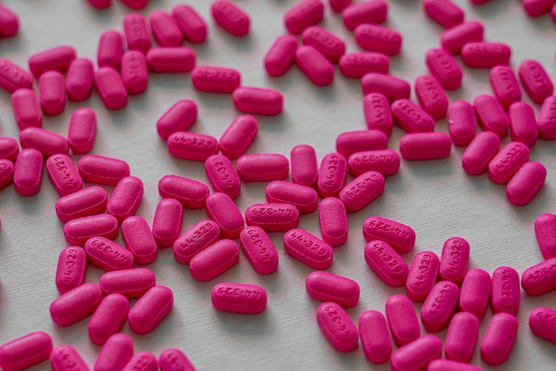 Close-up view of pink tablets scattered on a white table for medication and health treatment. - spring pollen allergies