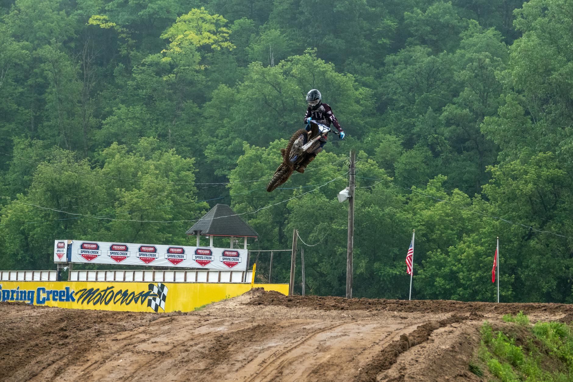 Motocross rider performing an aerial stunt at Spring Creek MX Park, surrounded by lush forest. - spring reset challenge