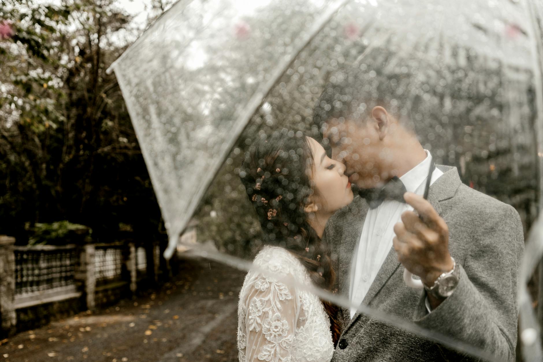 A couple shares a romantic kiss under an umbrella on a rainy day, symbolizing love and togetherness. - spring seasonal affective disorder