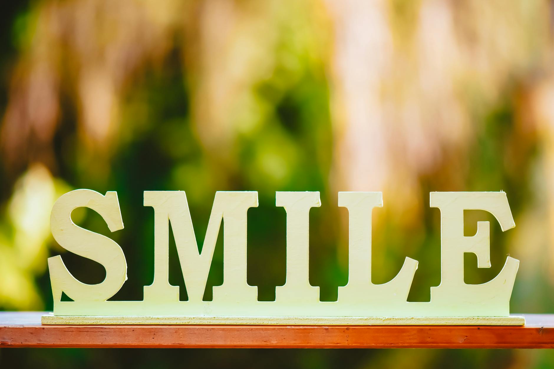 Wooden cutout letters spelling 'SMILE' against a soft, blurred background. Bright and optimistic. - spring sleep optimization