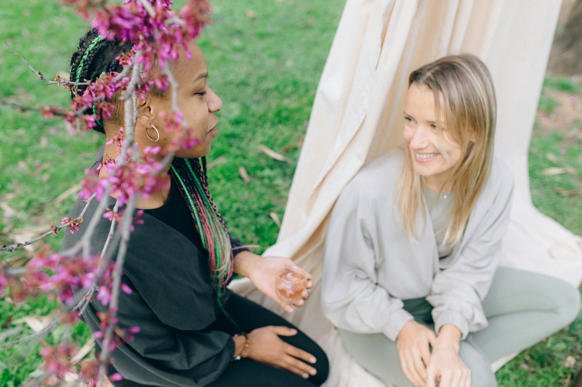 Two women enjoying a serene outdoor moment surrounded by spring blossoms. - spring wellness rituals