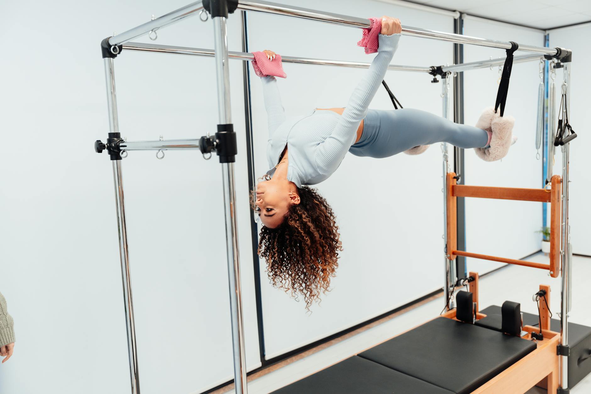 Fit woman doing pilates exercise on reformer equipment in a fitness studio. - standing pilates