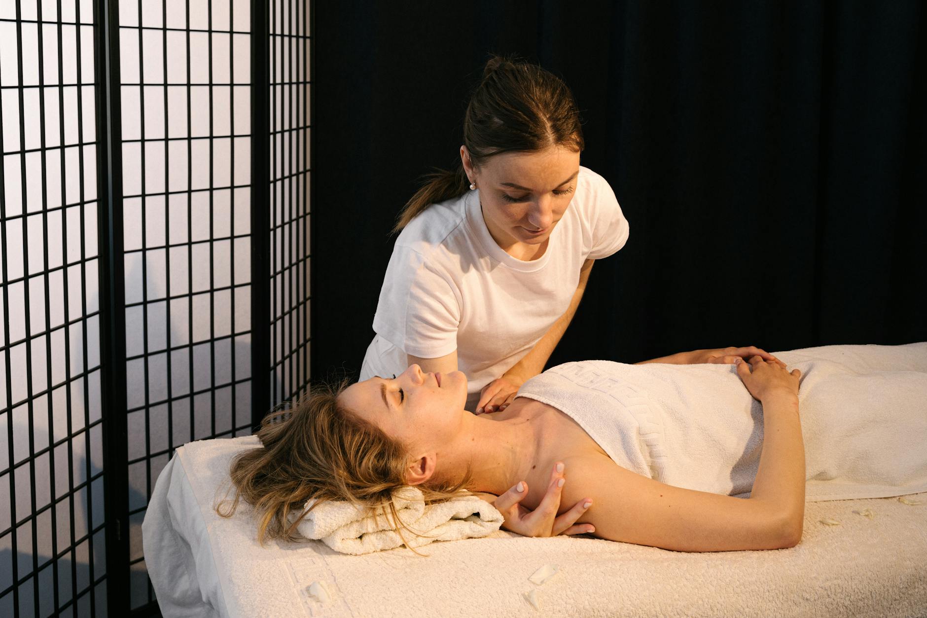 A masseuse provides therapeutic massage to a woman in a tranquil spa setting. - stress relief techniques