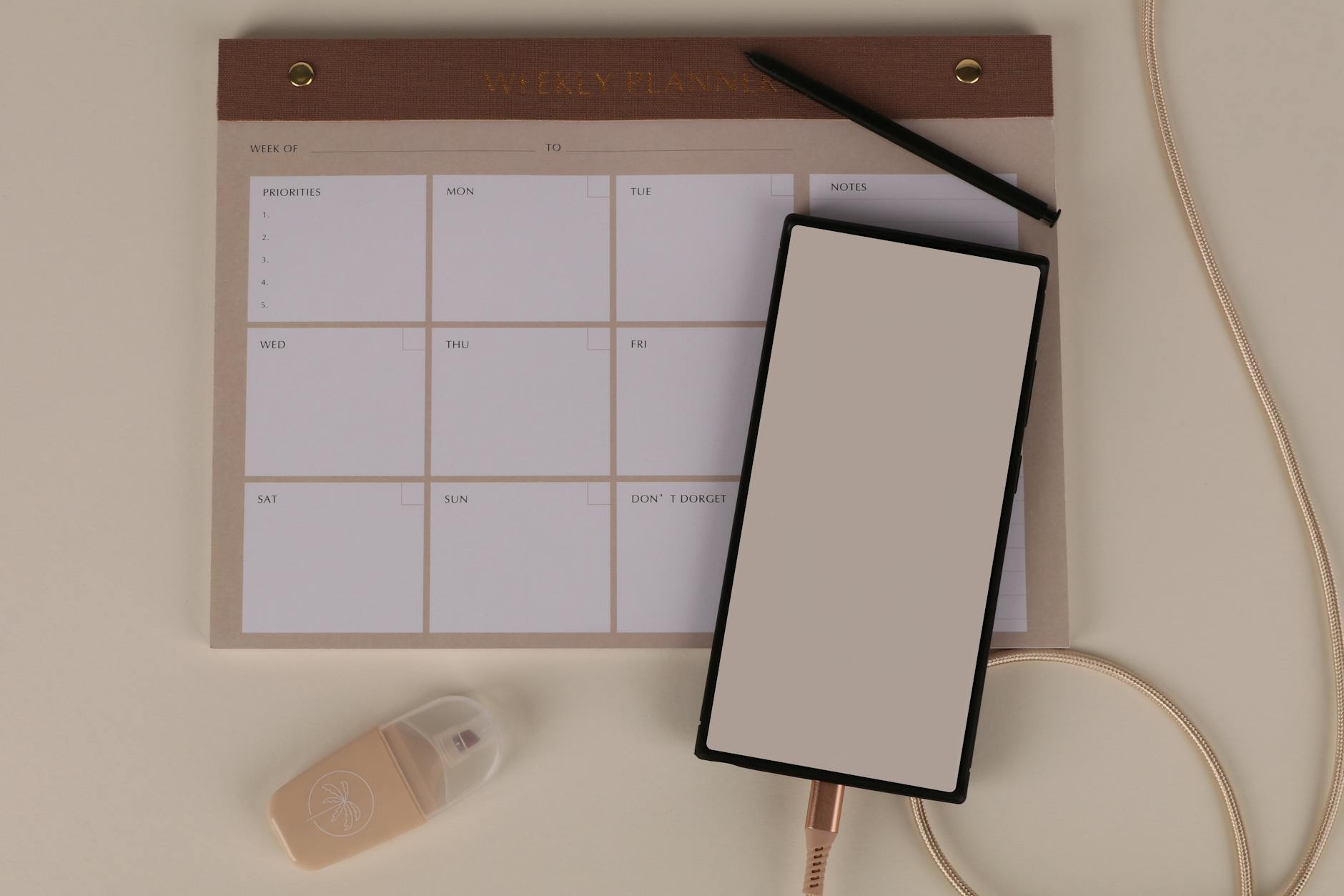 Flat lay of a minimalist desk setup featuring a weekly planner, smartphone, and stationery. - weekly workout plan