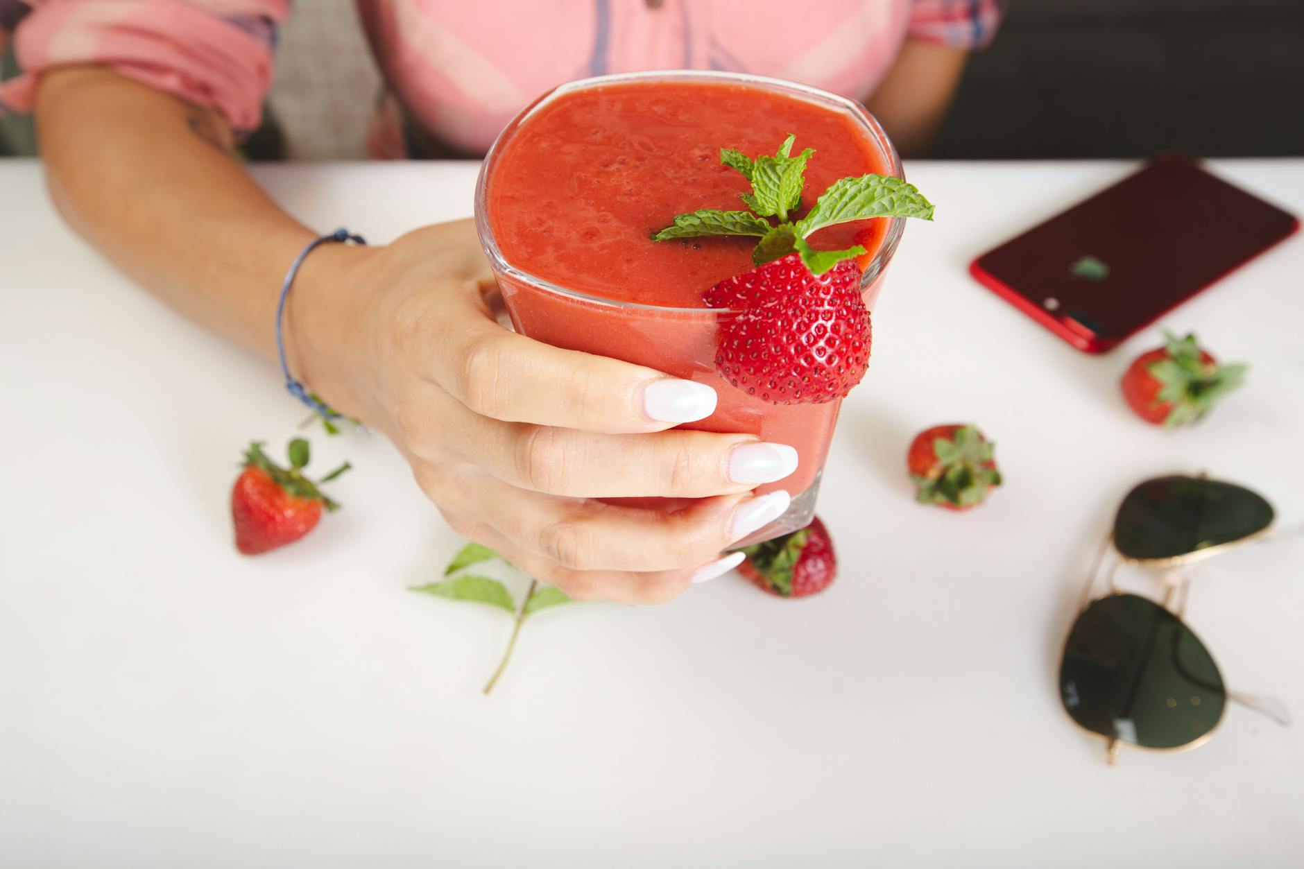 Hand holding a refreshing strawberry smoothie with fresh mint in a Dubai cafe. Perfect summer treat. - weight loss smoothies