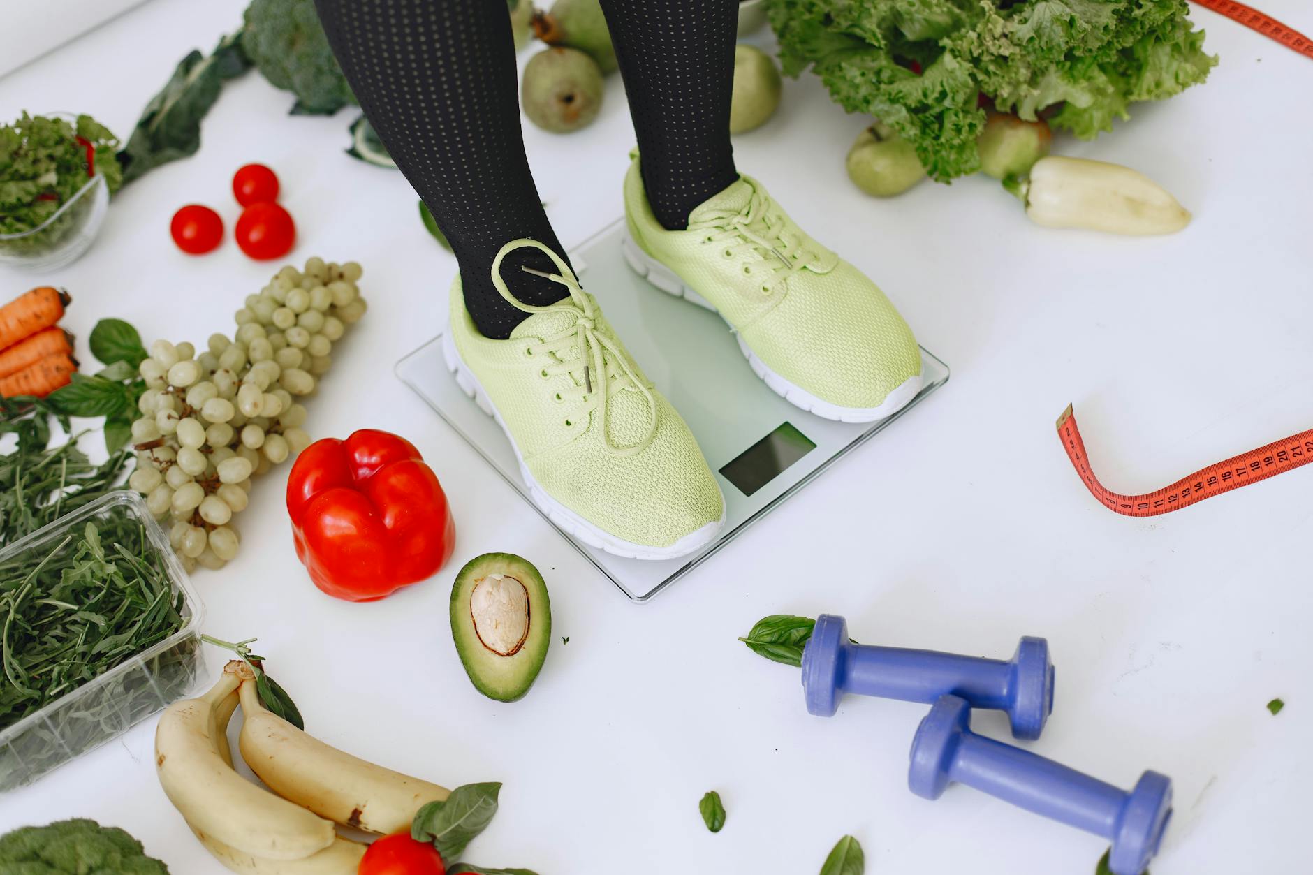 Person standing on scales surrounded by fresh produce and fitness equipment symbolizing a balanced lifestyle. - weight loss tumblr
