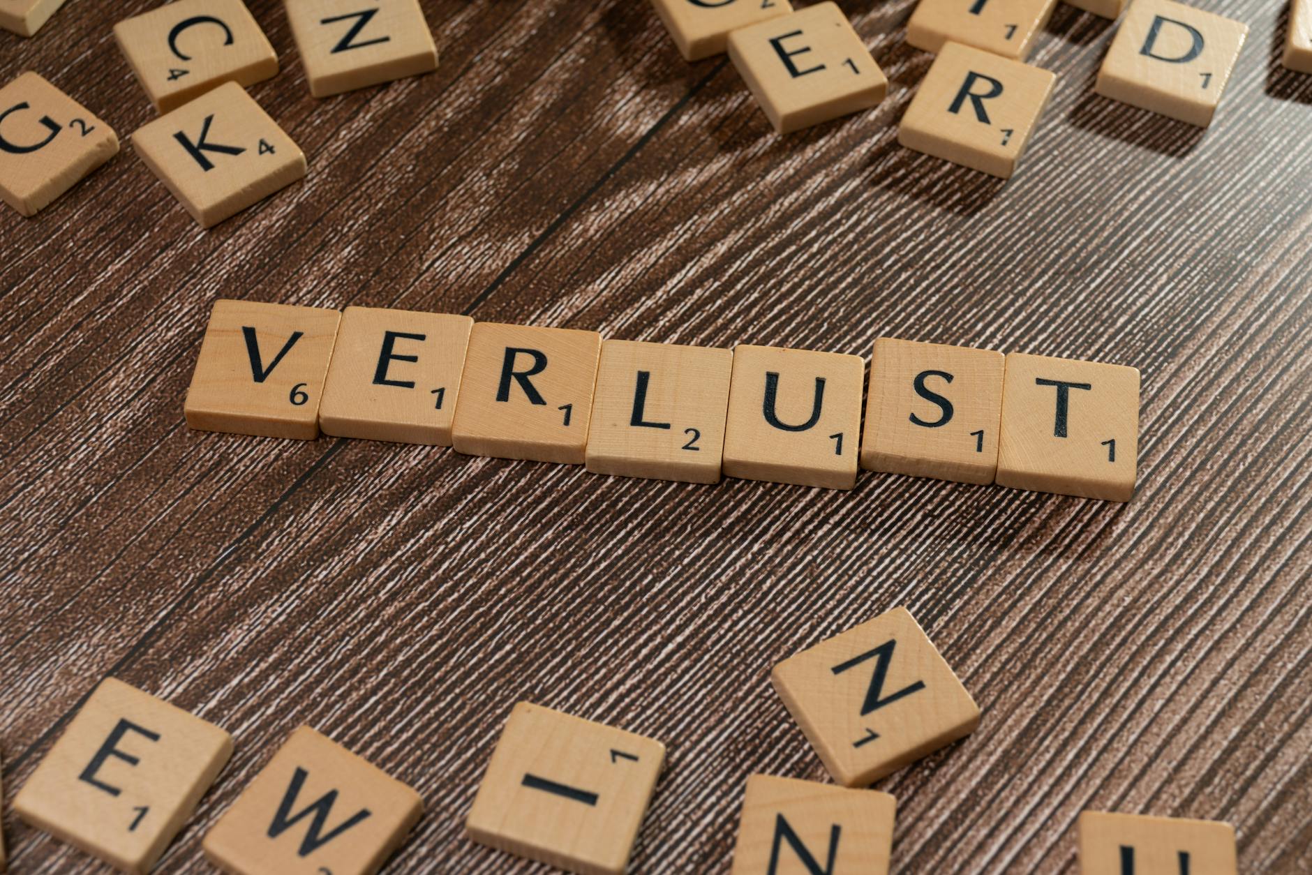 Scrabble tiles spelling 'Verlust' on a wooden table, symbolizing loss or financial context. - winter wellness slump