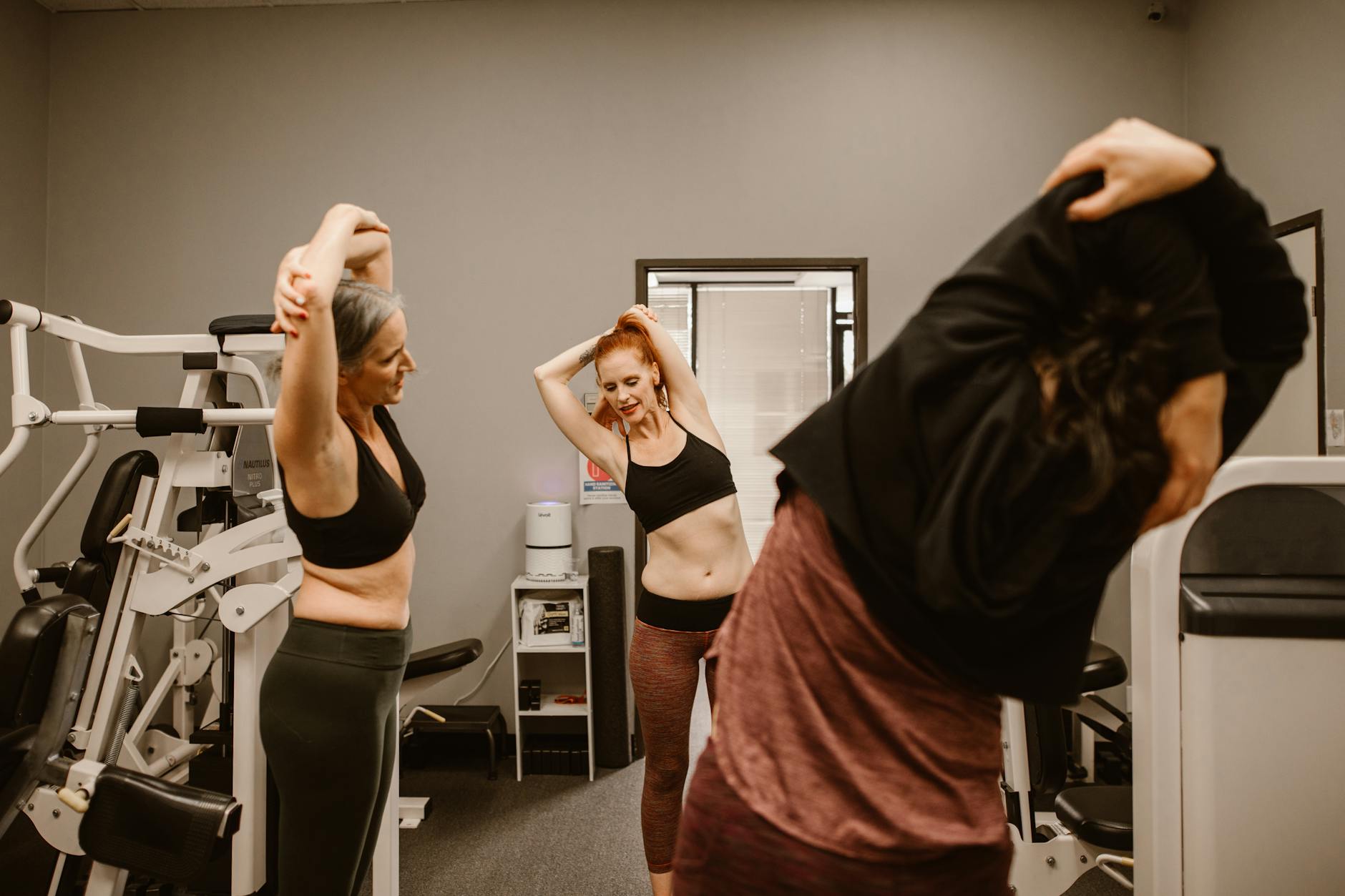 Three women stretching at the gym, promoting fitness and healthy lifestyles. - women's gym workout