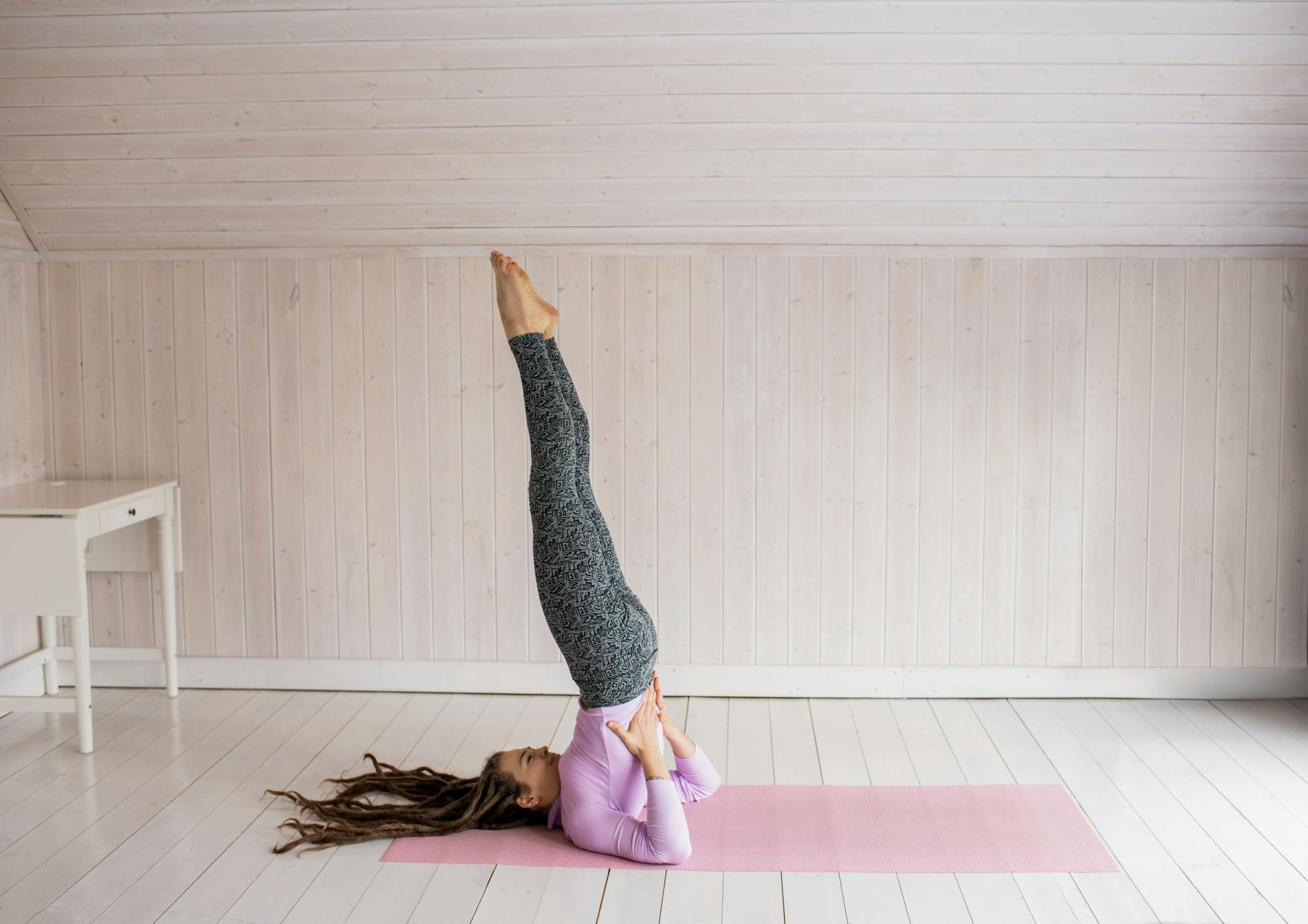 Woman in a yoga pose on a pink mat indoors, demonstrating flexibility and balance. - yoga stretching routine