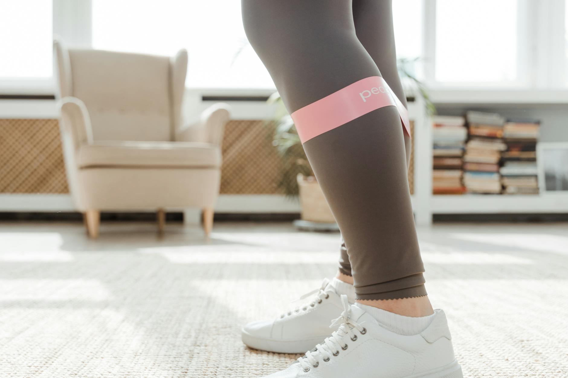 Close-up of legs using a resistance band for stretching exercise indoors. - yoga for weight loss