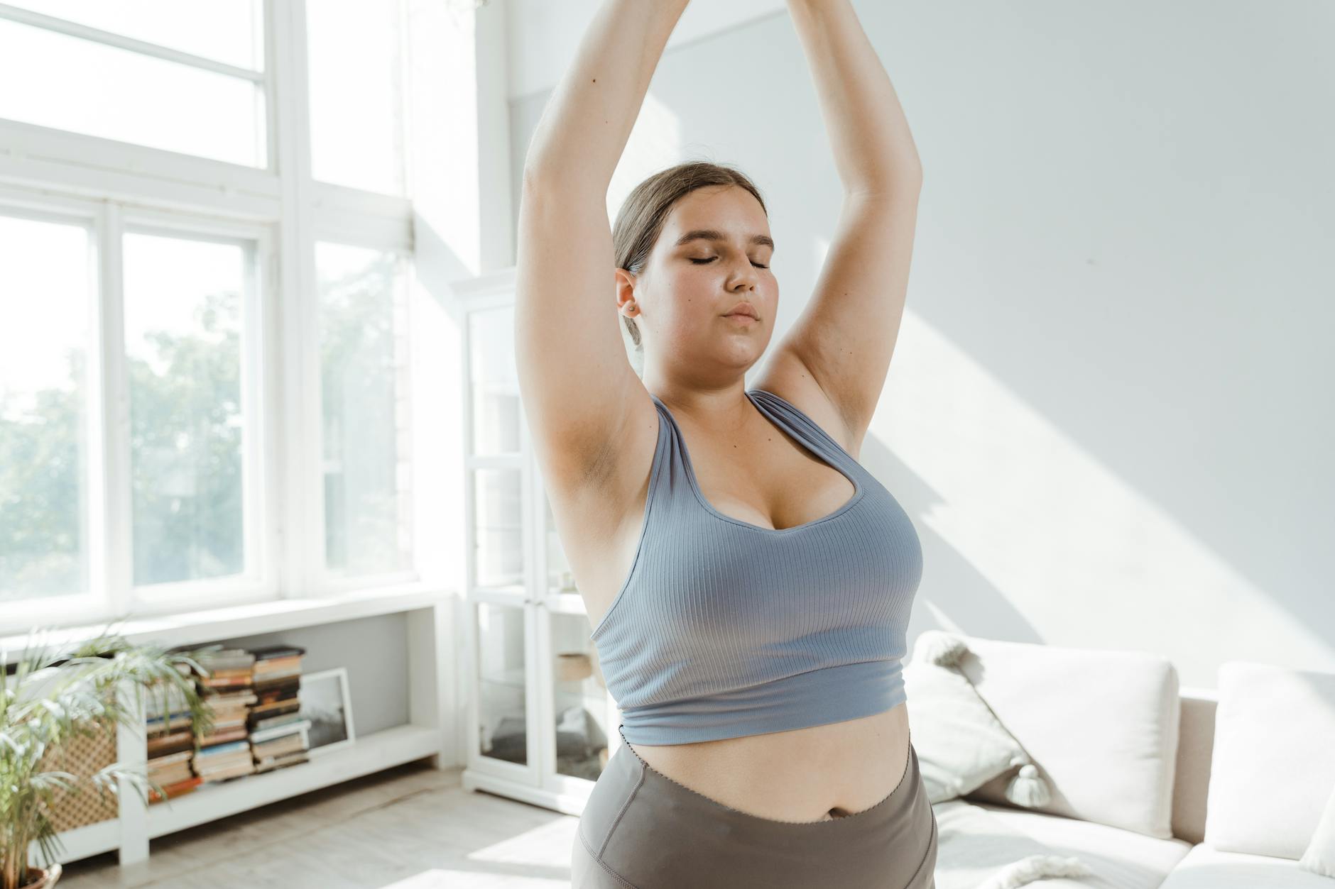 A plus size woman practicing body positivity and stretching at home for a healthy lifestyle. - yoga for weight loss