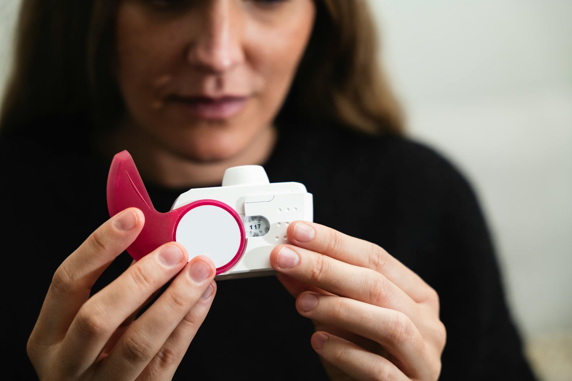 Close-up of a woman holding a medical inhaler device for respiratory conditions. - allergy relief diet