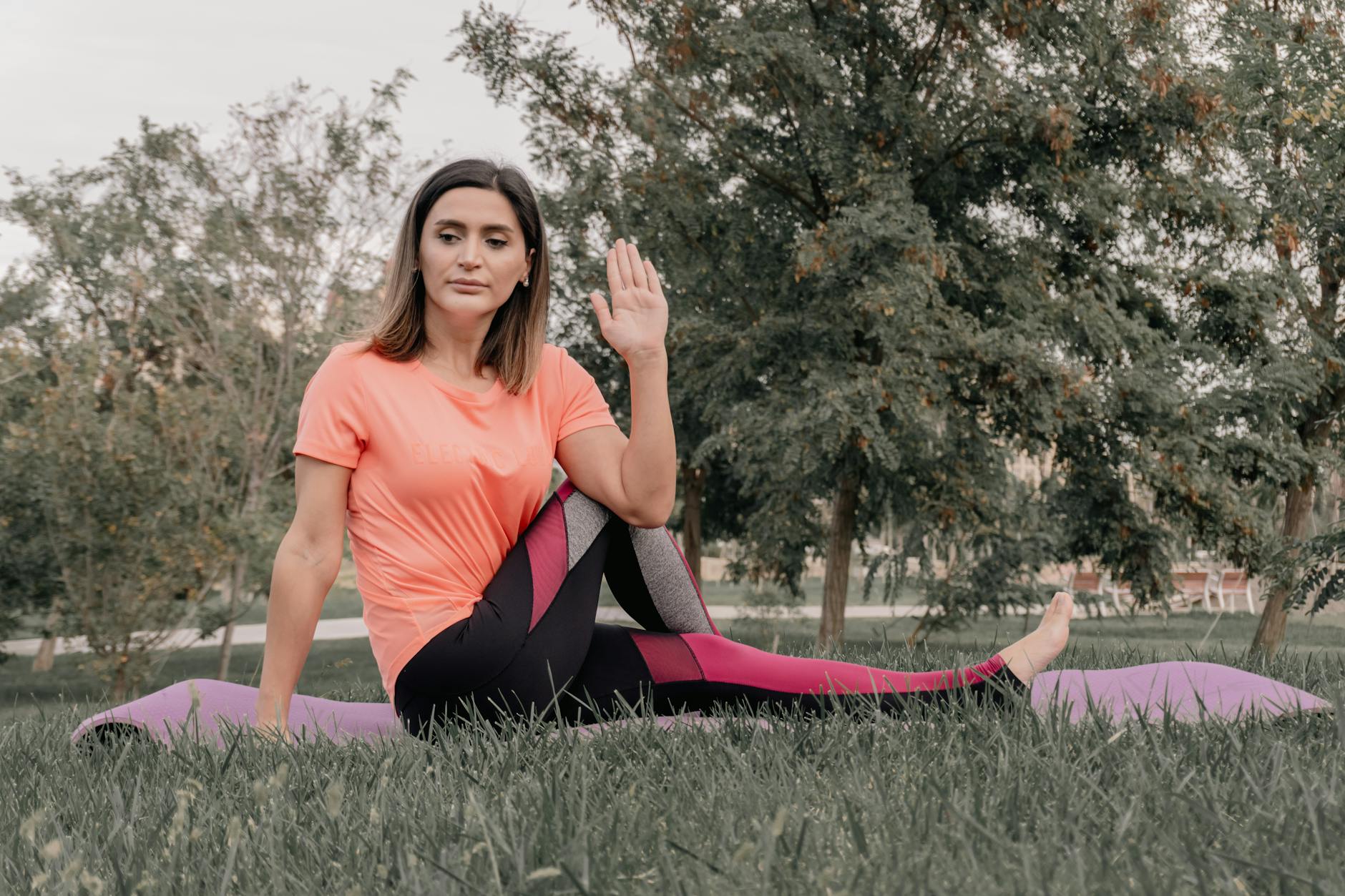 Adult woman practicing yoga on a mat in a park setting, displaying focused concentration. - beginner yoga routine