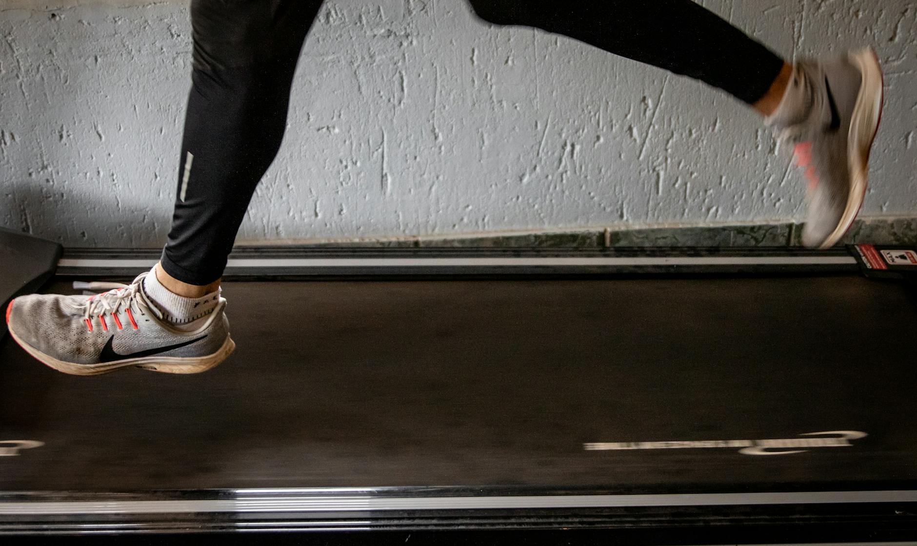 Close-up of a woman's legs running on a treadmill indoors, focusing on fitness and exercise. - best running shoes