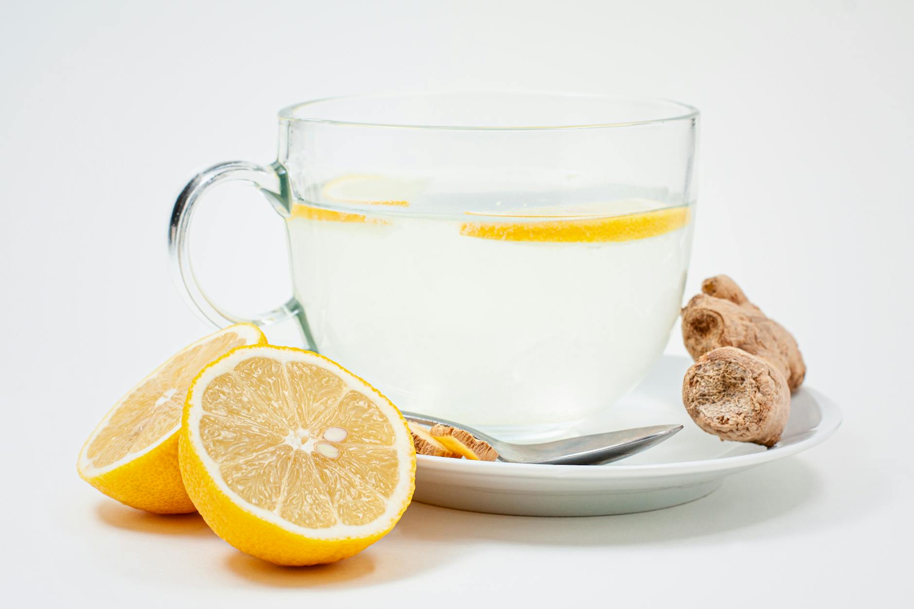 A soothing cup of lemon ginger tea with fresh lemon slices and ginger root on a white background. - body detox diet