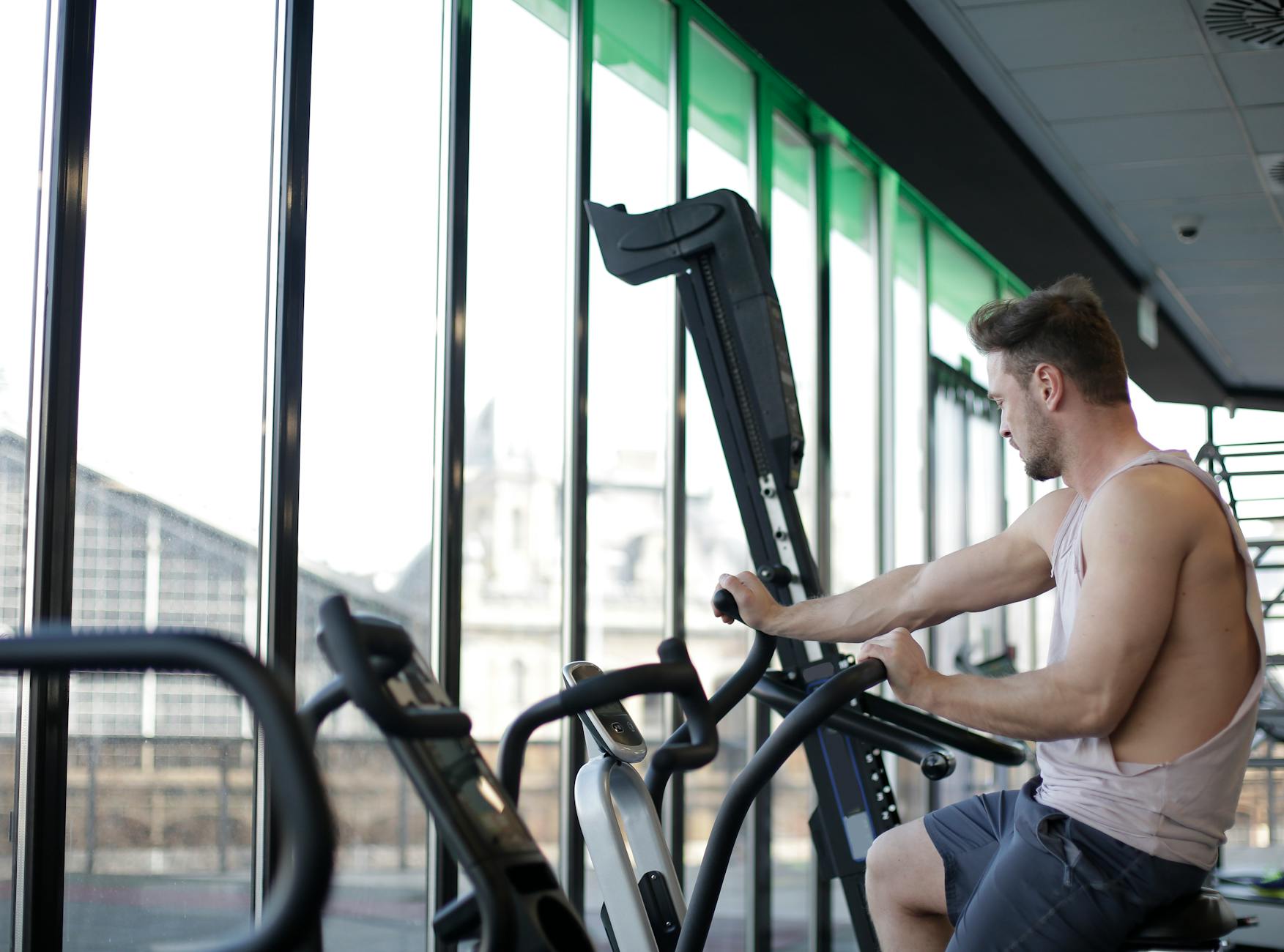 Adult man working out on a stationary bike in a modern gym, focusing on fitness and strength. - gym cardio machines