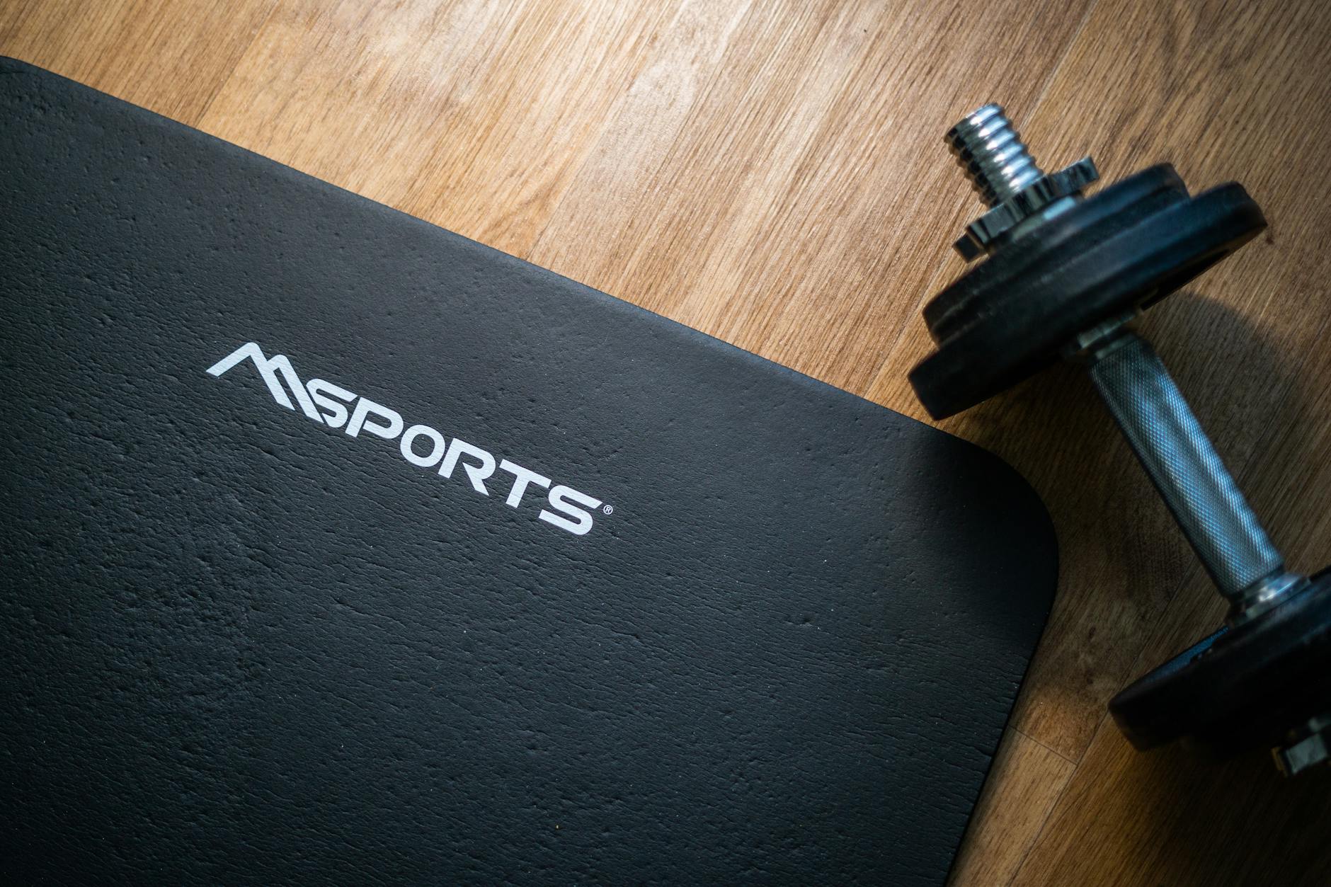 Flat lay of a gym mat and dumbbell on wooden floor, ideal for indoor workouts. - at home strength