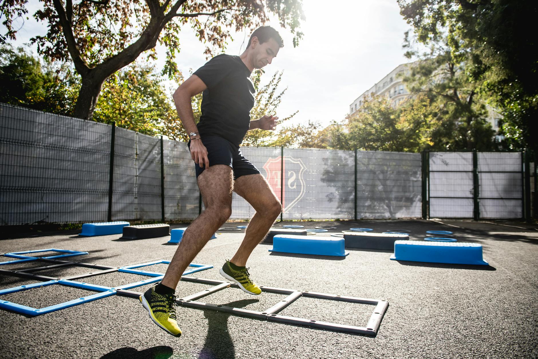 A man performing agility drills outdoors in a sunny park setting. - interval training cardio
