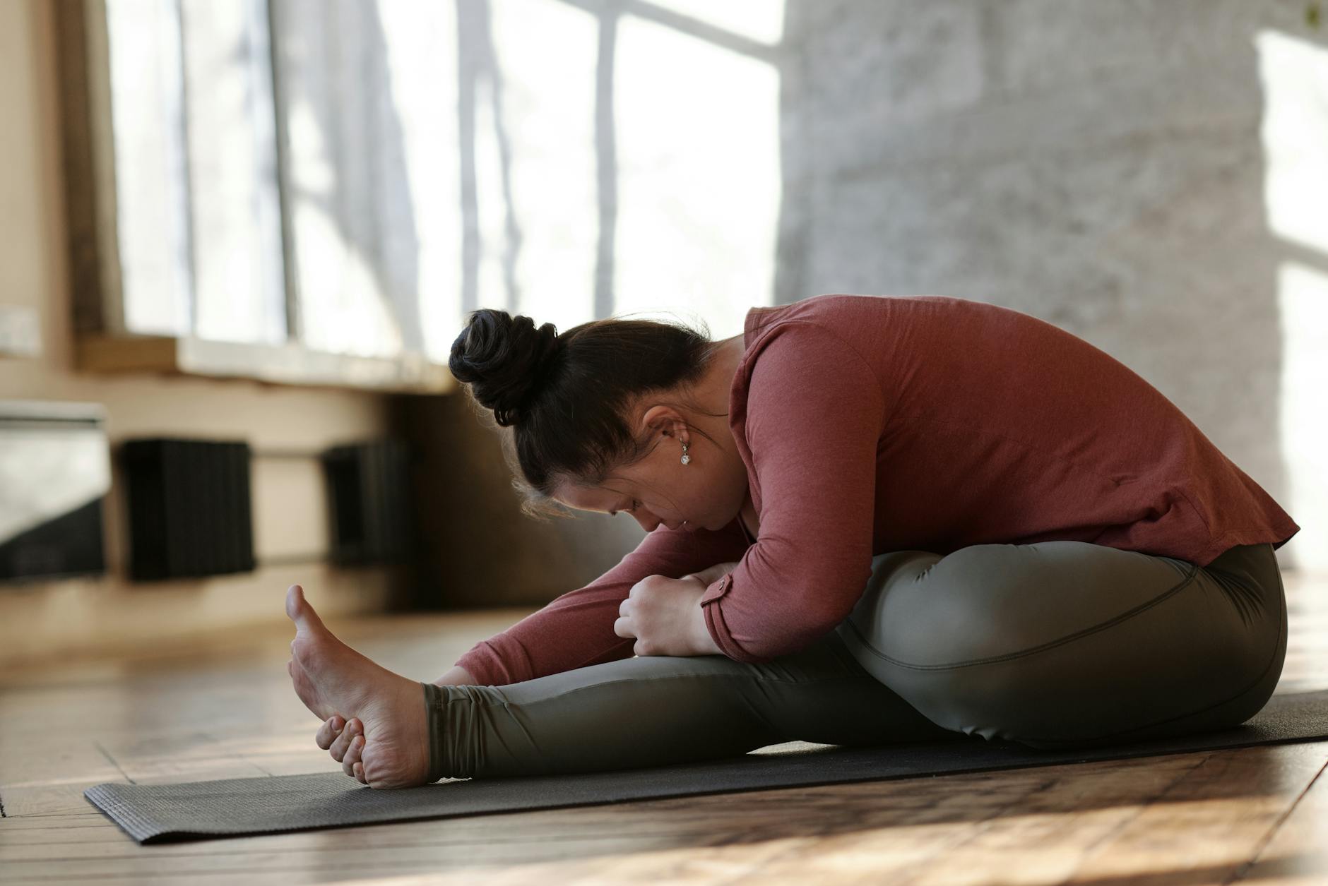 Woman with Down syndrome practicing yoga indoors, focusing on relaxation and wellness. - leg flexibility exercises