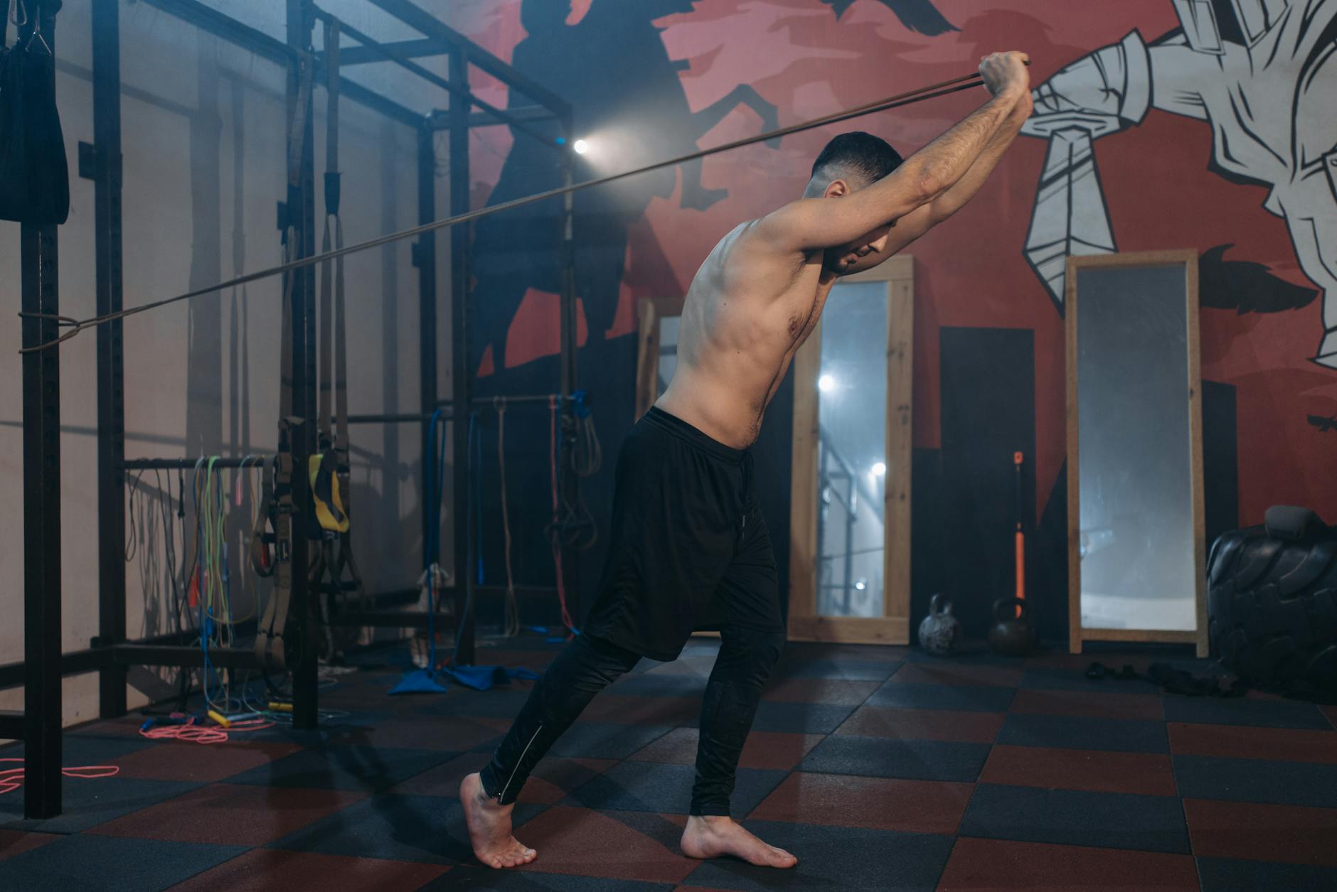 Shirtless man engages in a dynamic rope workout at a contemporary indoor gym. - posture exercises gym