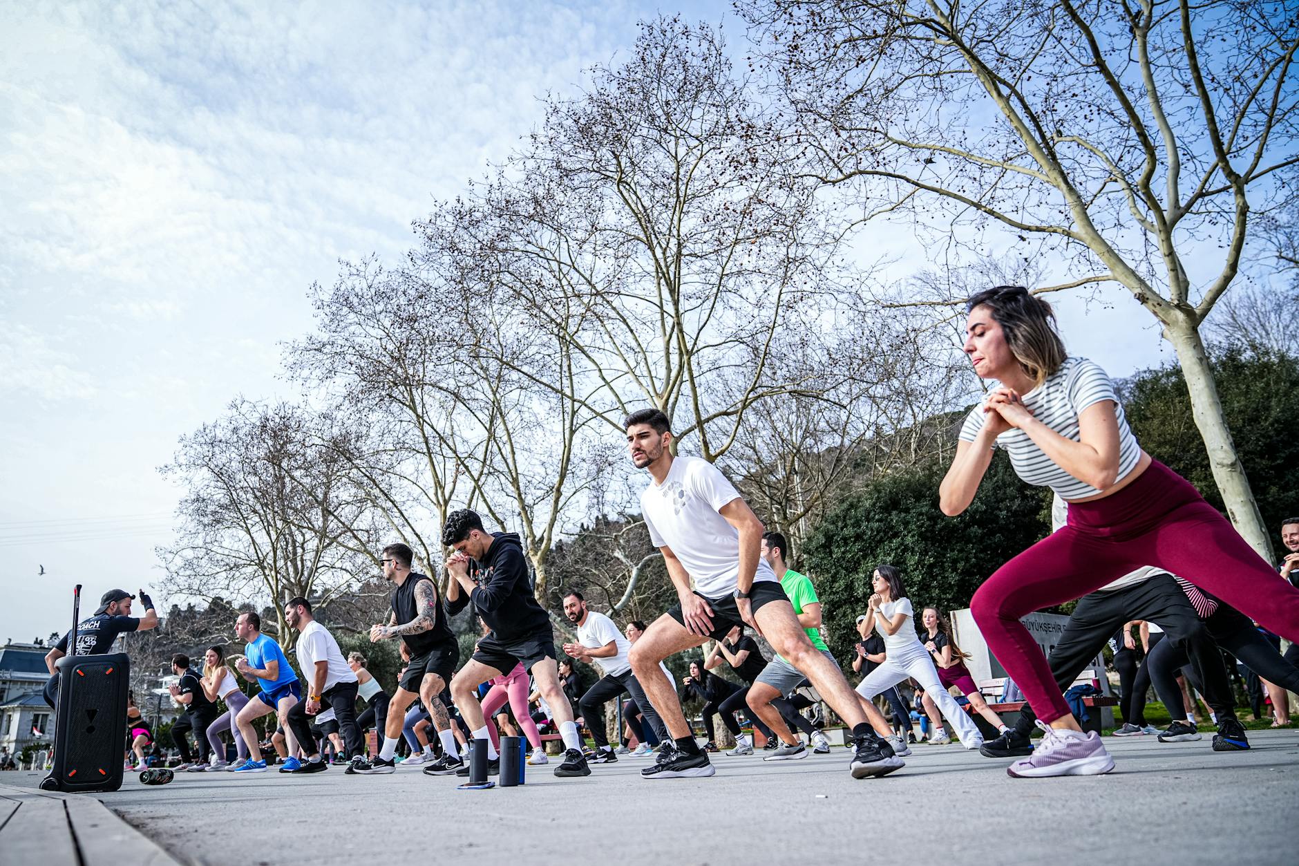 A lively outdoor fitness class in İstanbul with diverse participants engaged in exercise routines. - spring outdoor workouts