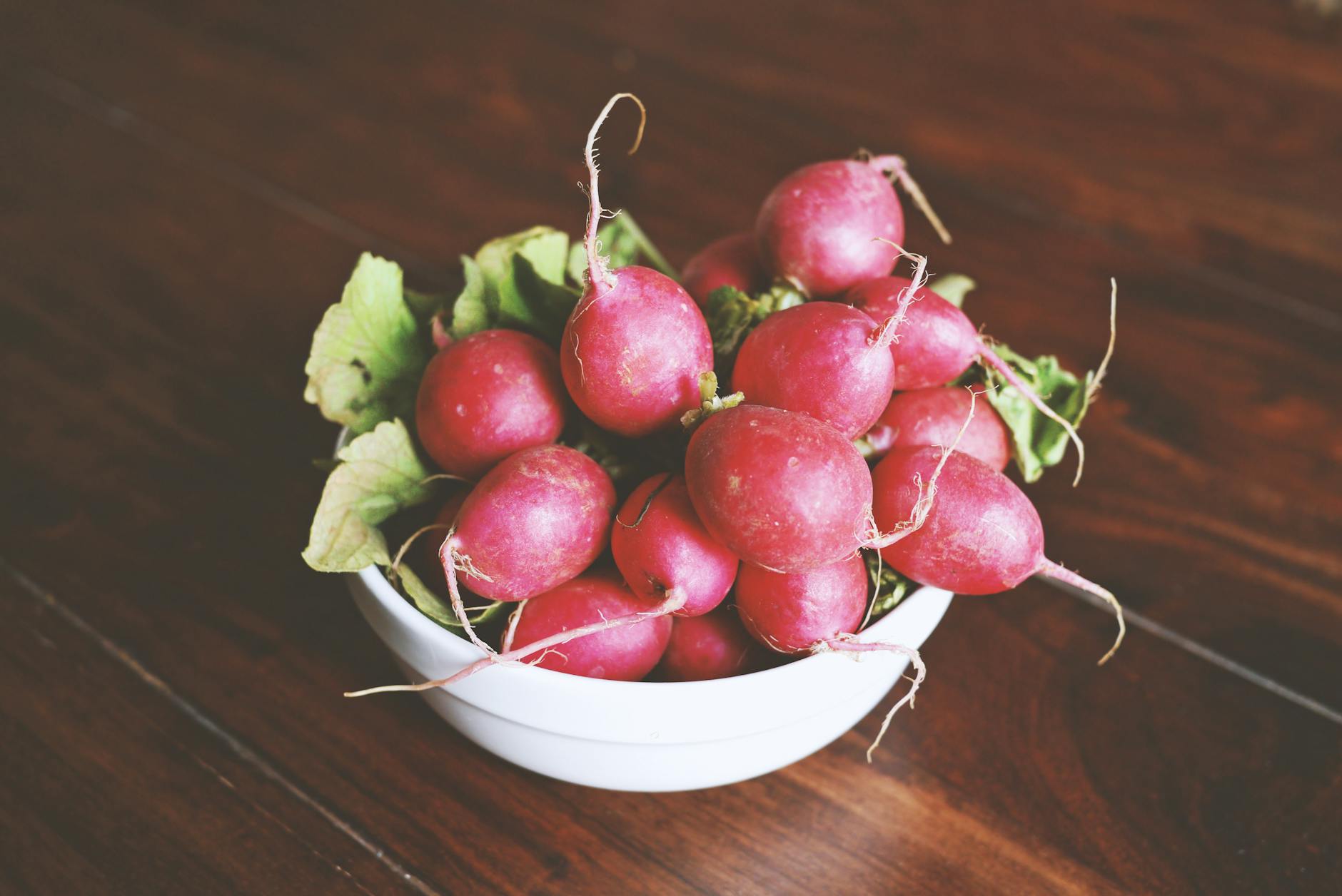 A close-up of vibrant red radishes in a bowl, showcasing their fresh and healthy appeal. - spring produce health