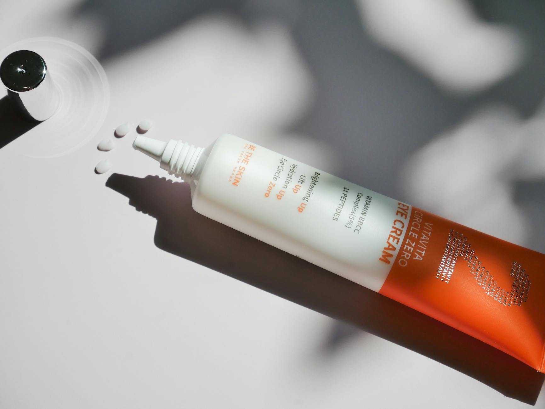 Close-up of skincare cream tube on a minimalist white surface with shadows. - spring skincare routine