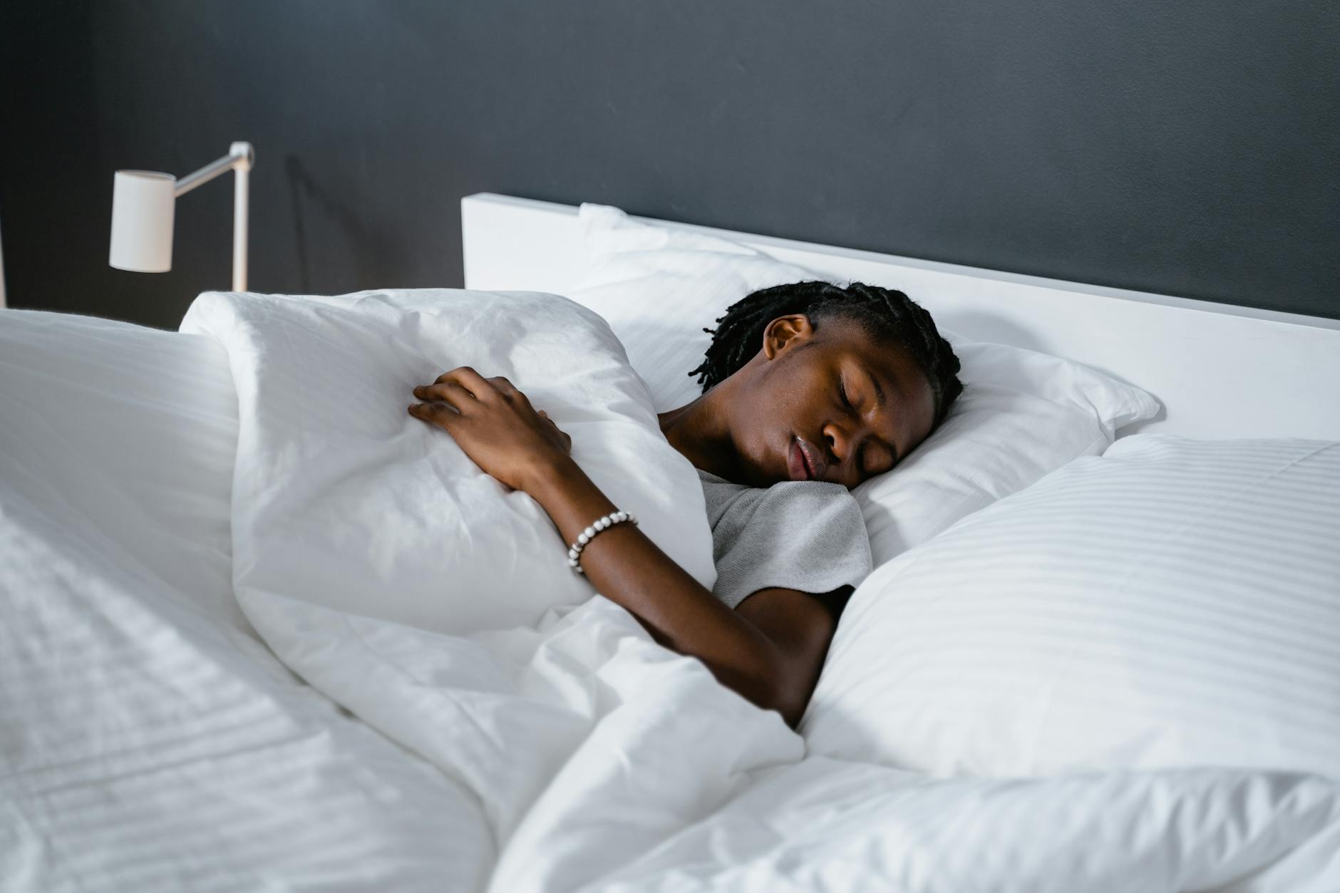 A man sleeping peacefully under a white blanket in a cozy bedroom. - spring sleep reset