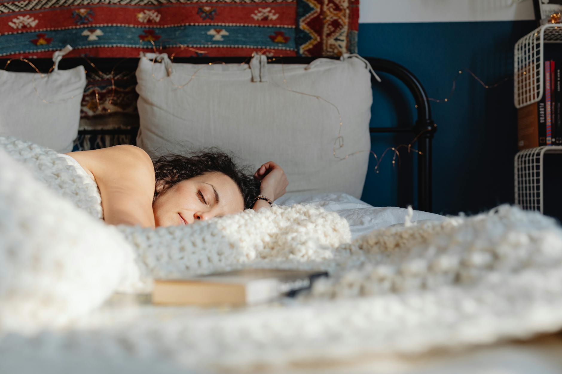 A woman peacefully sleeping on her side in a cozy, sunlit bedroom with decorative elements. - spring sleep schedule