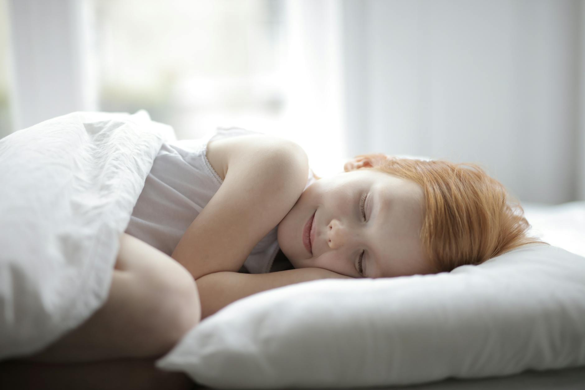 A young girl peacefully sleeping in a bright bedroom, conveying comfort and relaxation. - spring sleep schedule