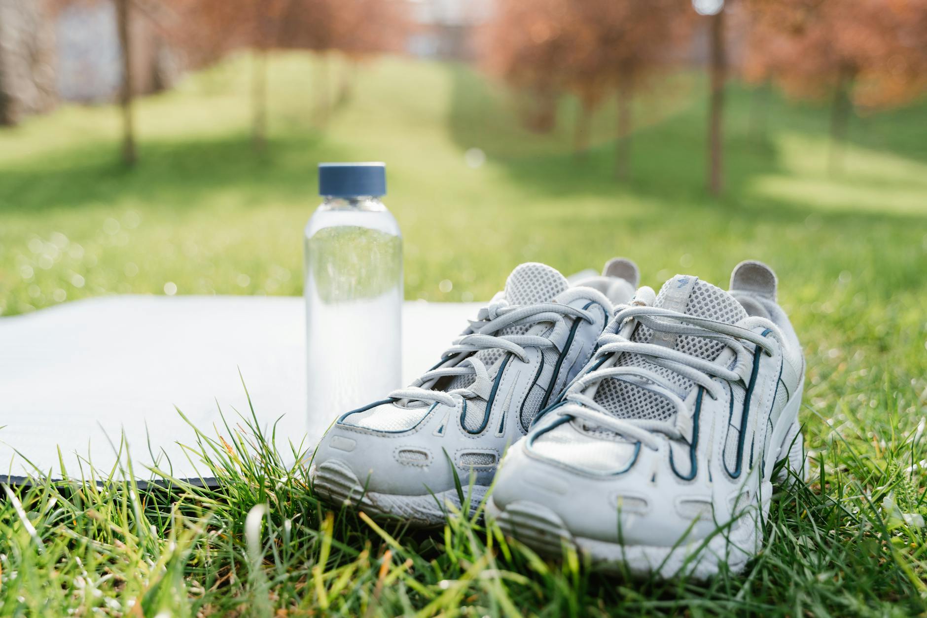 A close-up of white sneakers and a water bottle, ideal for sporty lifestyle themes. - spring workout hydration