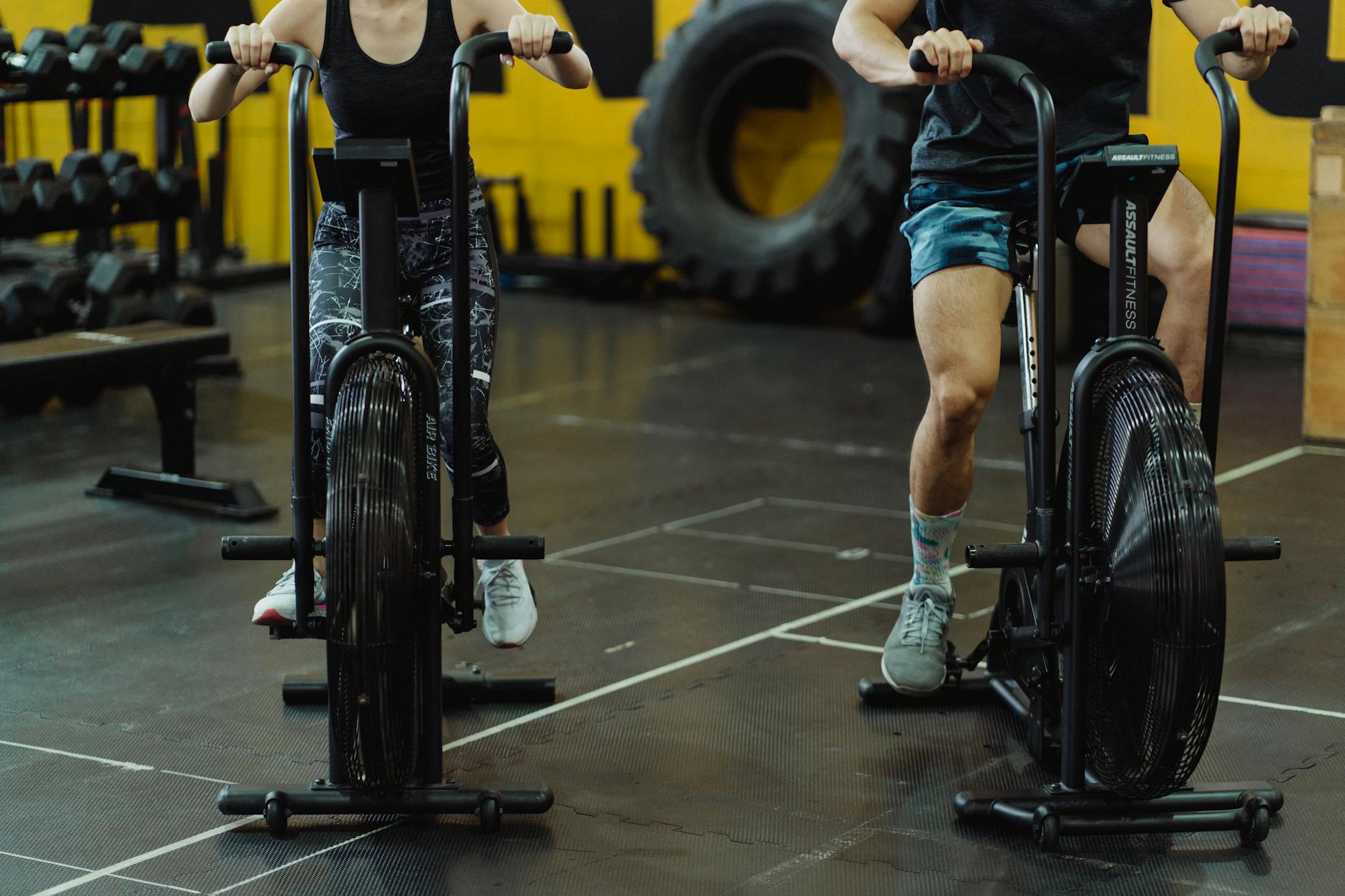 Two people exercising on stationary bikes at a modern gym. - advanced hiit workouts