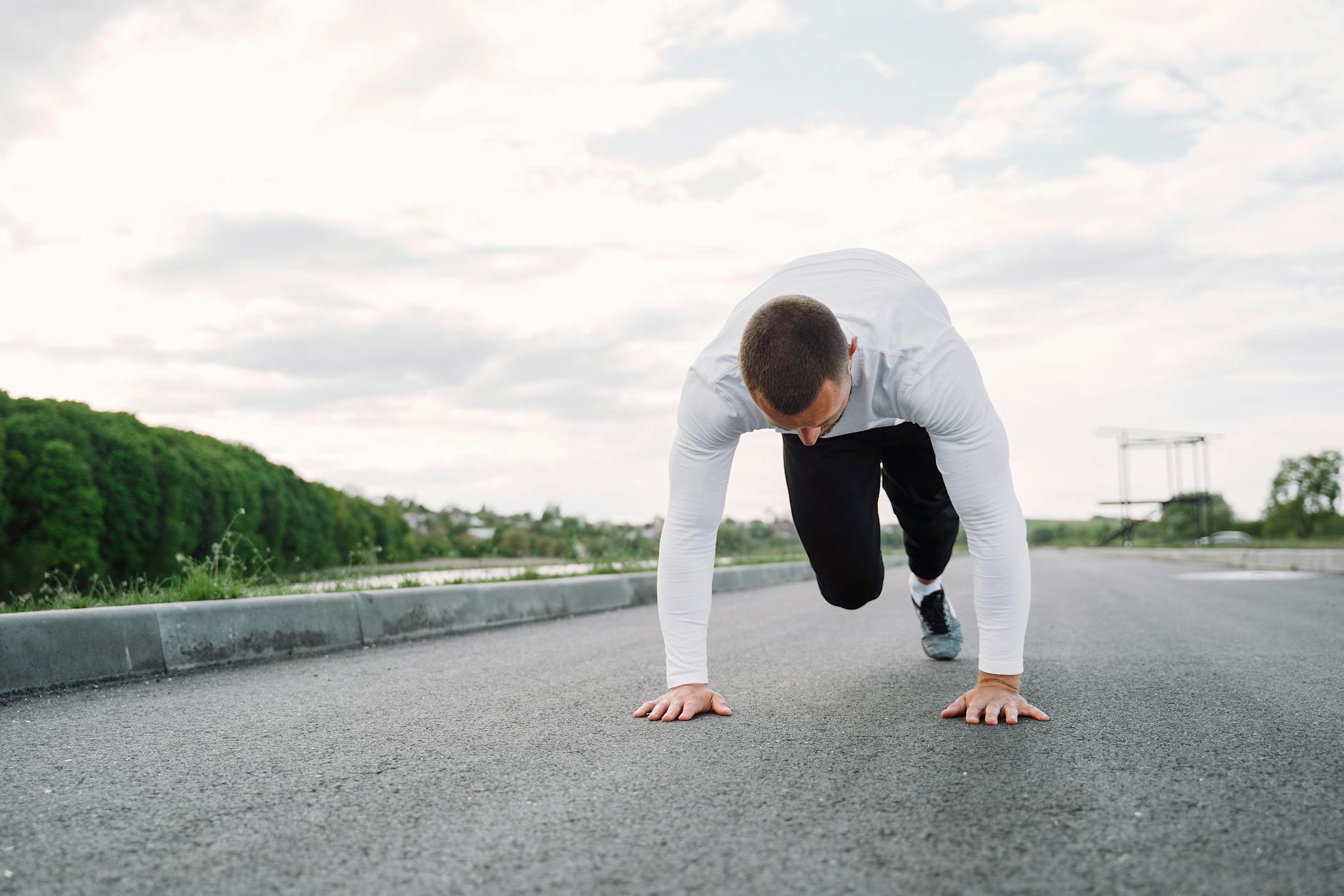 A man in sportswear begins his workout on an outdoor road, showcasing fitness and determination. - advanced hiit workouts