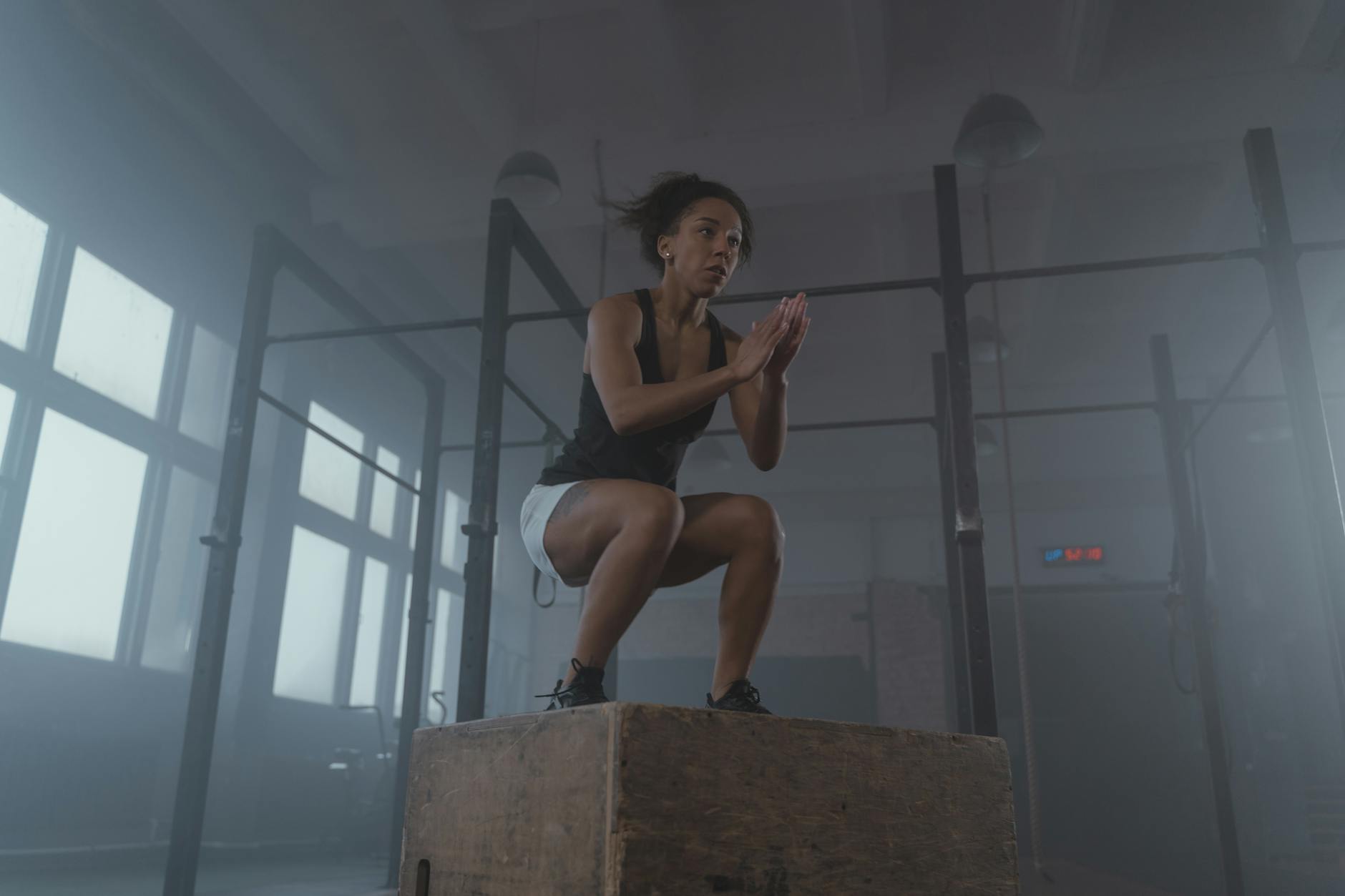A determined woman executing a box jump in an indoor gym setting, showcasing strength and fitness. - advanced hiit workouts