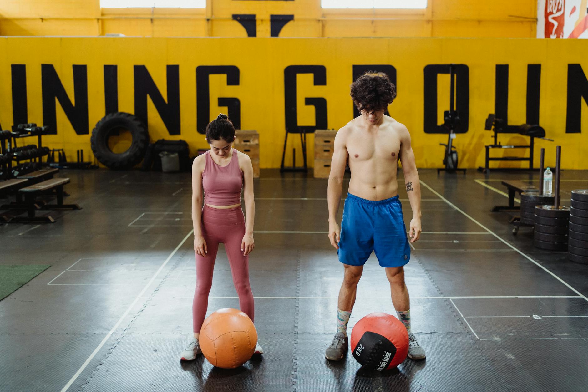 Shirtless man and woman in activewear exercising with medicine balls at the gym. - best gold standard pre workout
