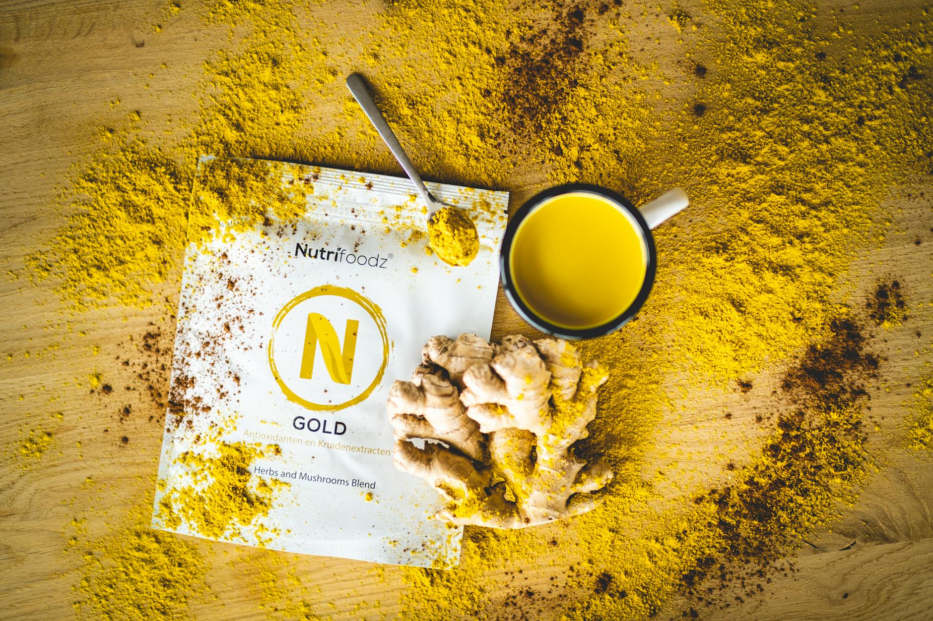 A flat lay of ginger tea with NutriFoodz blend powder, spoon, and ginger root. - boost immunity naturally