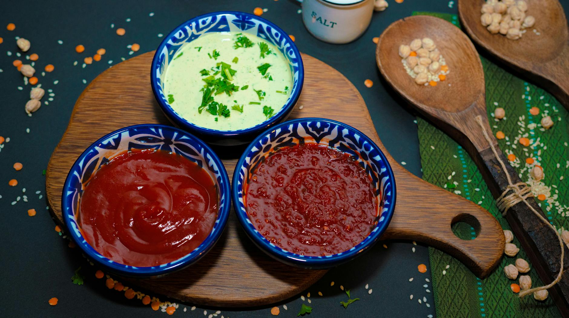 Colorful assortment of sauces in blue ceramic bowls on a wooden board, perfect for snacks. - easy vegan recipes