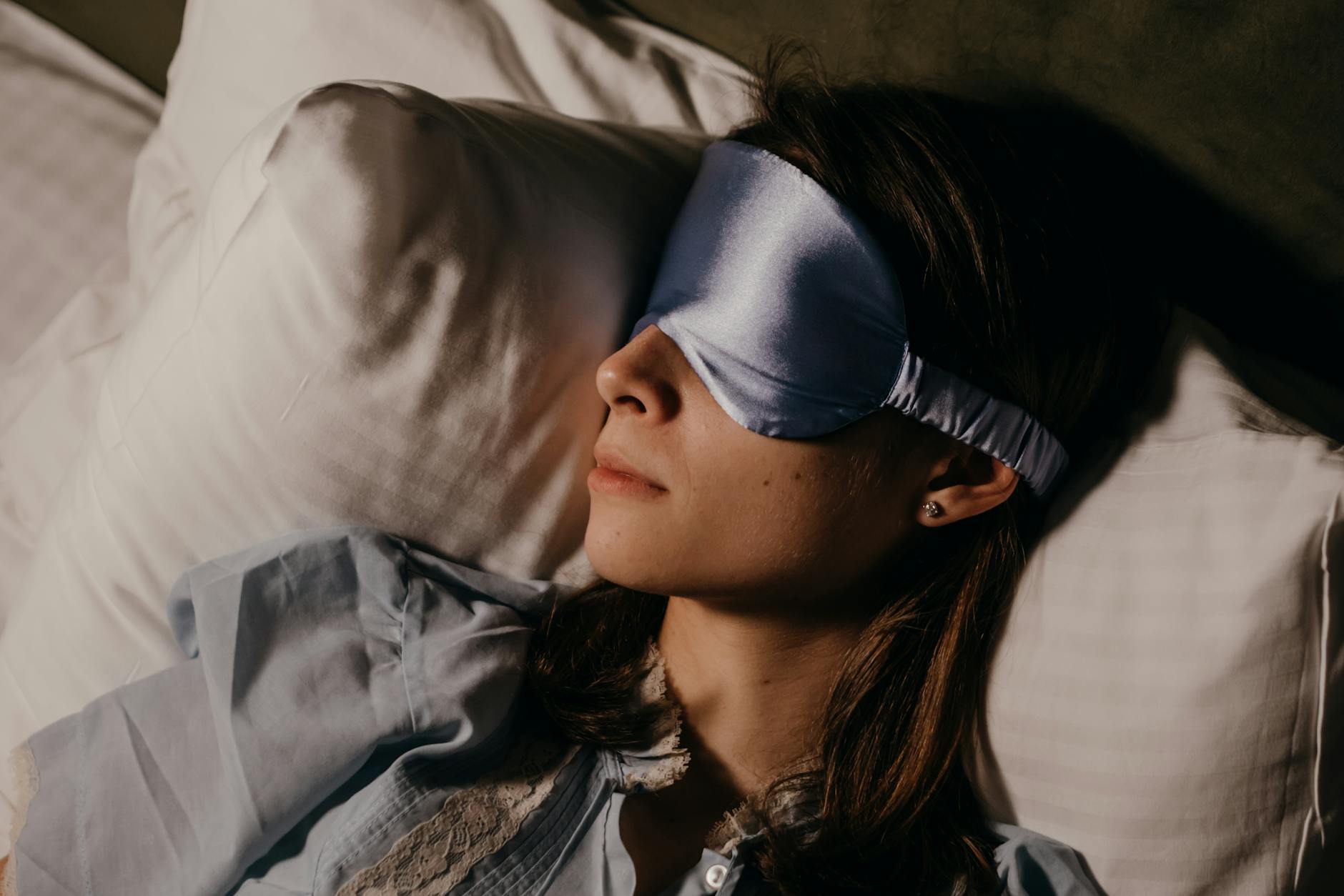 A woman peacefully sleeping indoors wearing a silk eye mask, capturing calm and relaxation. - improve sleep quality