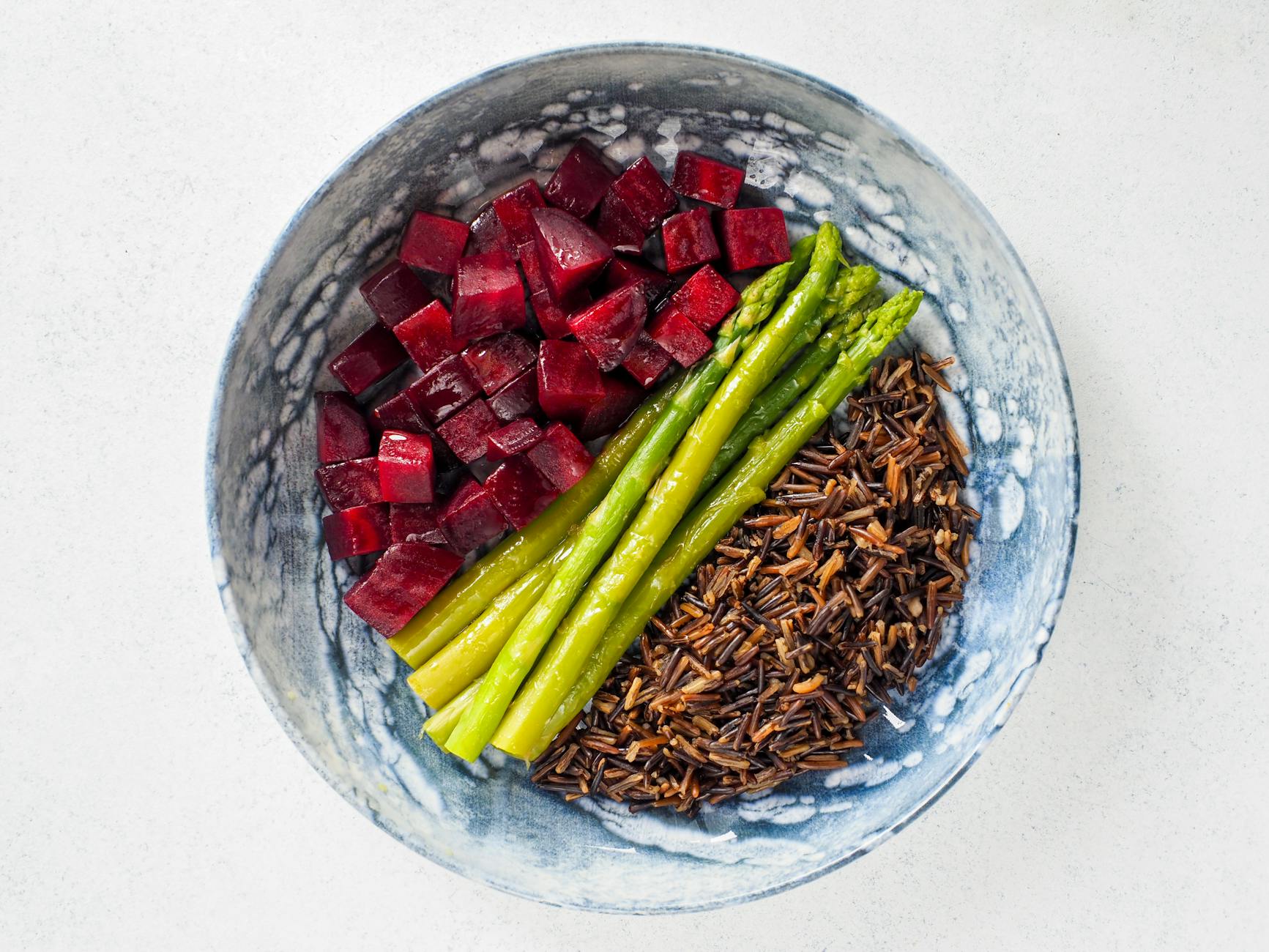 Top view of a nutritious vegan meal featuring beets, asparagus, and wild rice in a decorative bowl. - macronutrient balance spring