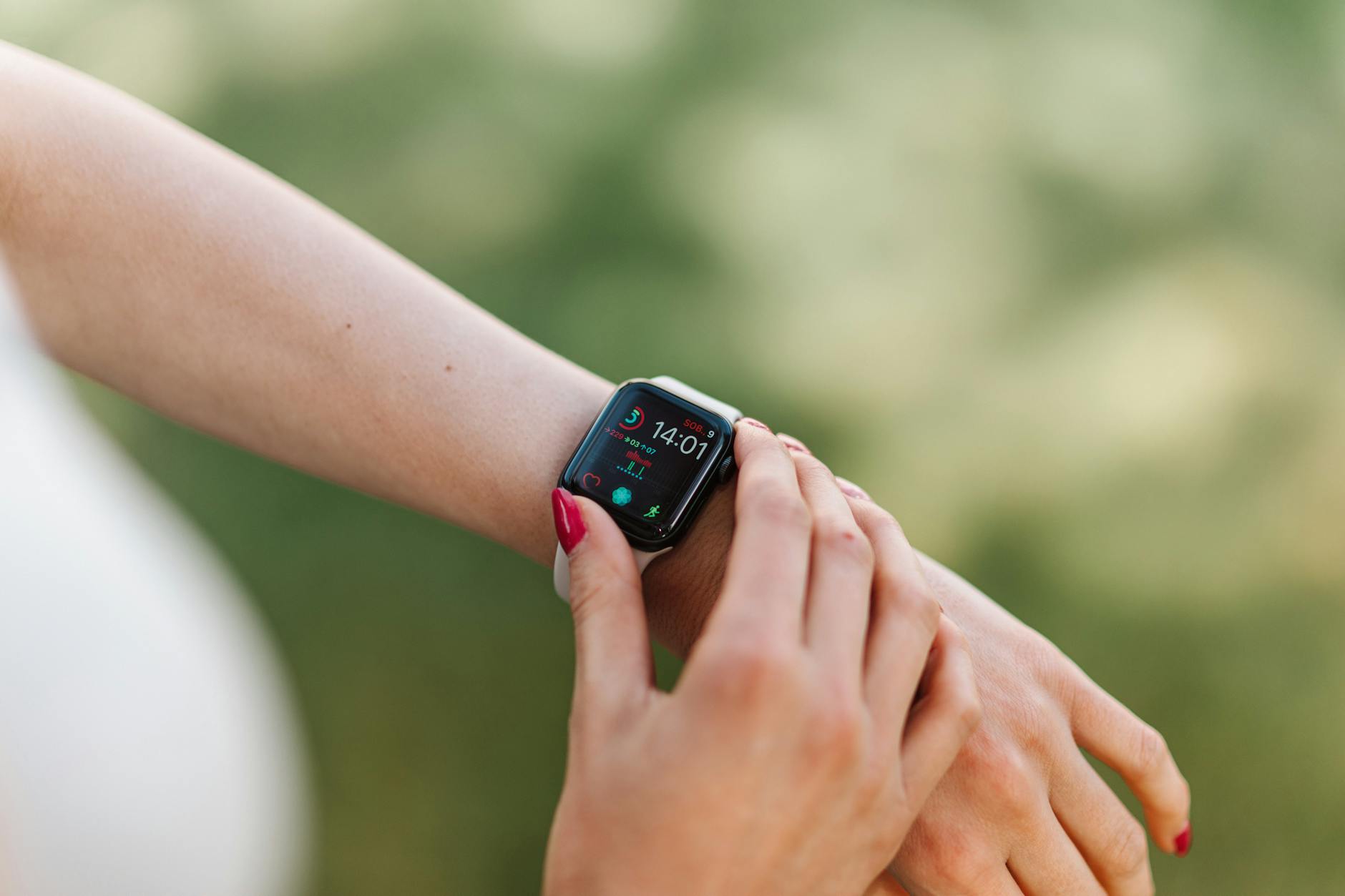 Woman adjusting smartwatch with manicured nails outdoors, focusing on fitness app. - nutrient timing fitness