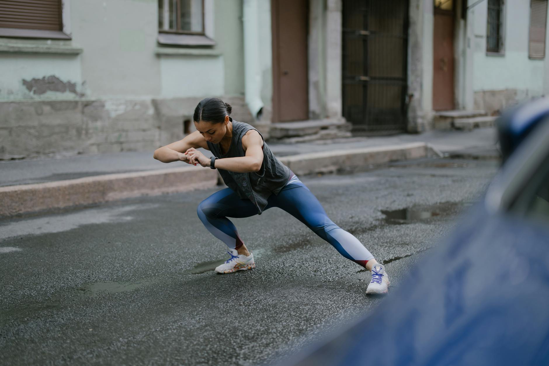 A woman doing stretching exercises on a wet urban street, embracing fitness in an outdoor setting. - outdoor cardio workouts