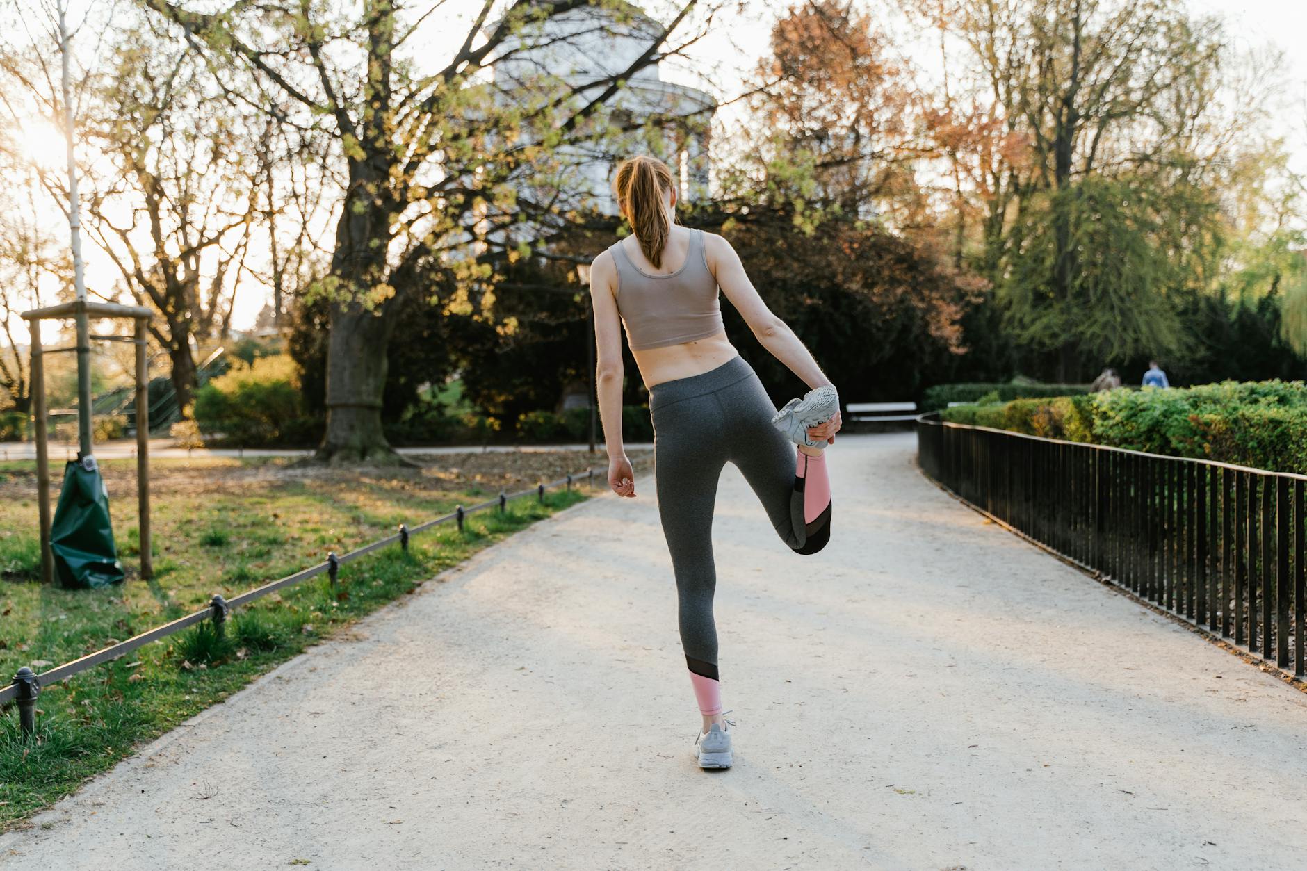 A woman performs a stretching exercise in a park setting, showcasing fitness and a healthy lifestyle. - outdoor cardio workouts